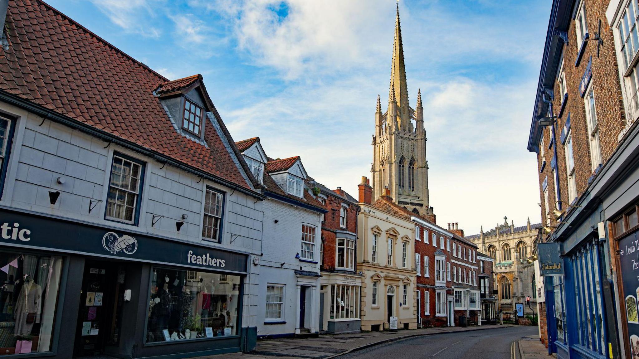 View of St James' Church at the end of a street lined with historical buildings - some of which have been painted.