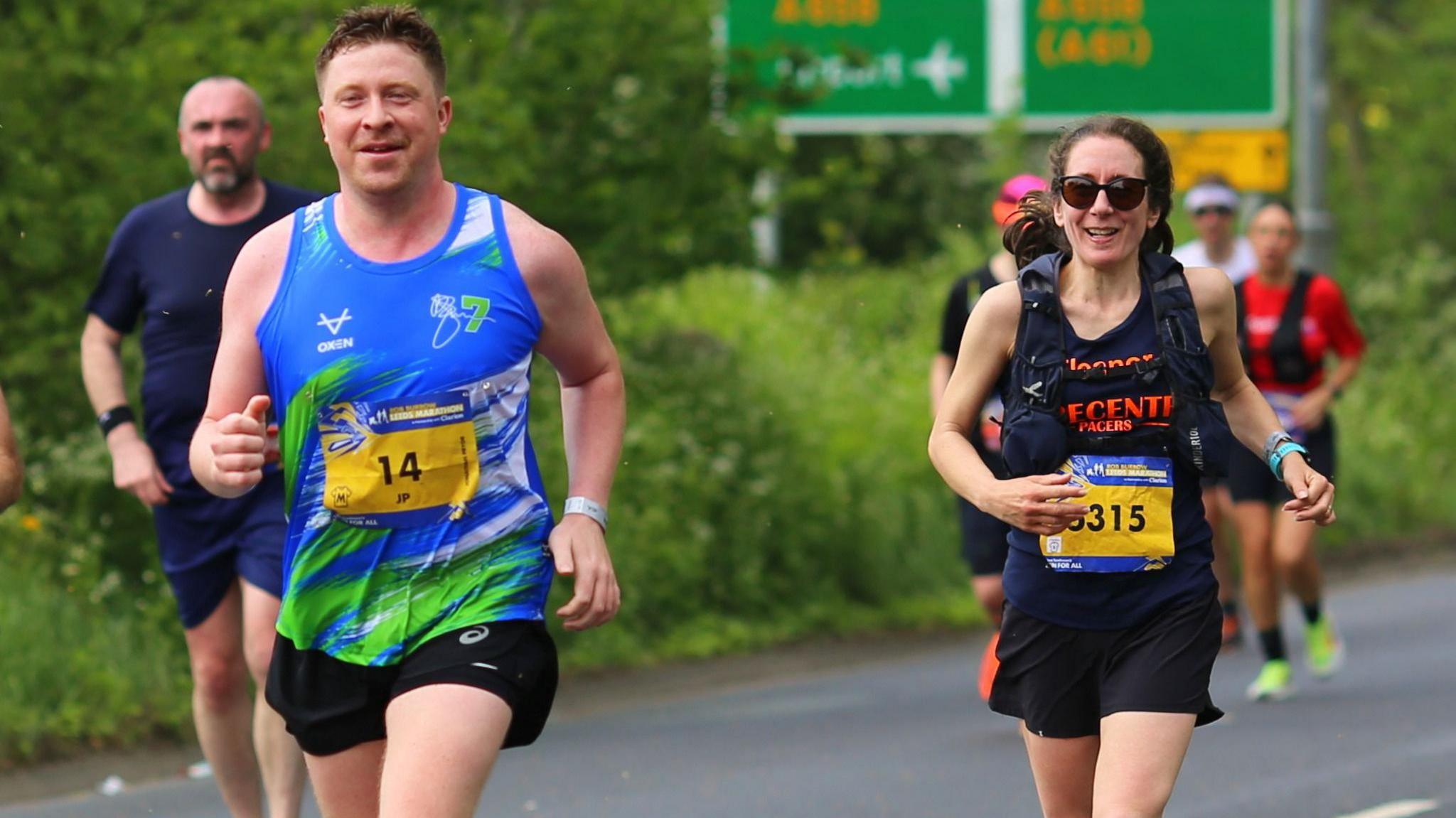 Councillor Eleanor Thomson runs in a black running vest and shorts behind fellow councillor Jonathan Pryor, in a blue running vest and shorts.