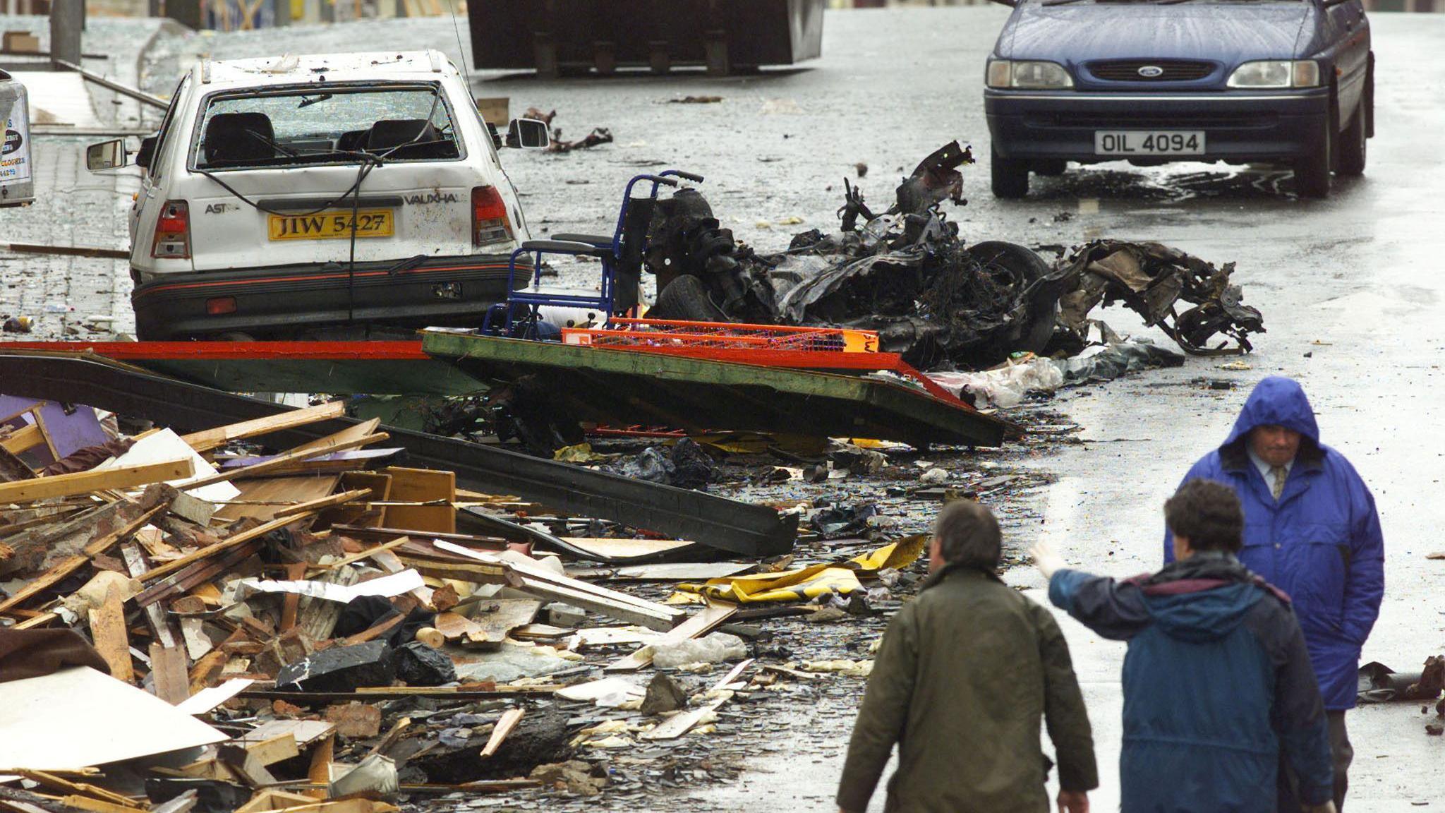 The wreckage of the Omagh Bomb on the town's main street as people look on