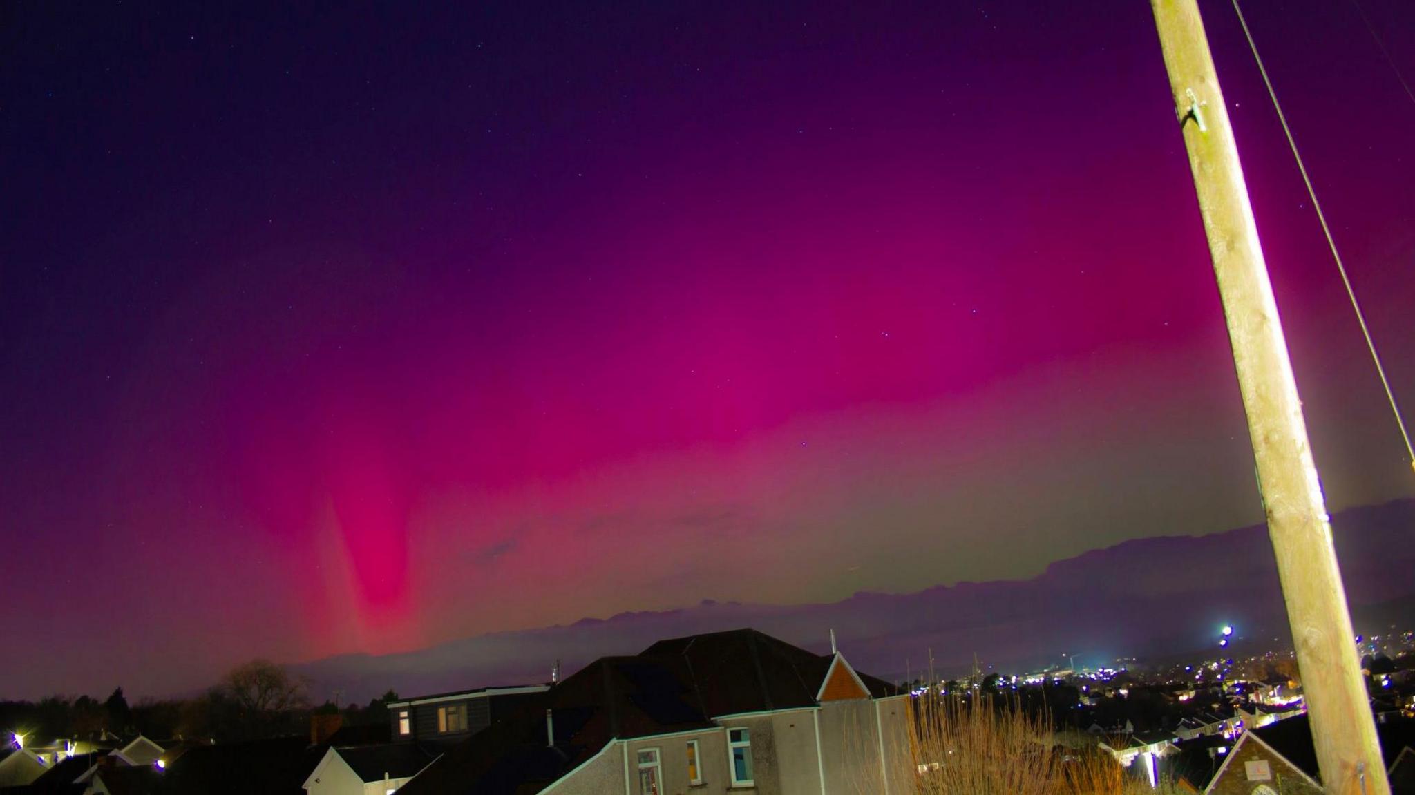 Houses and illuminated city with purple and pink sky above Morriston, Swansea