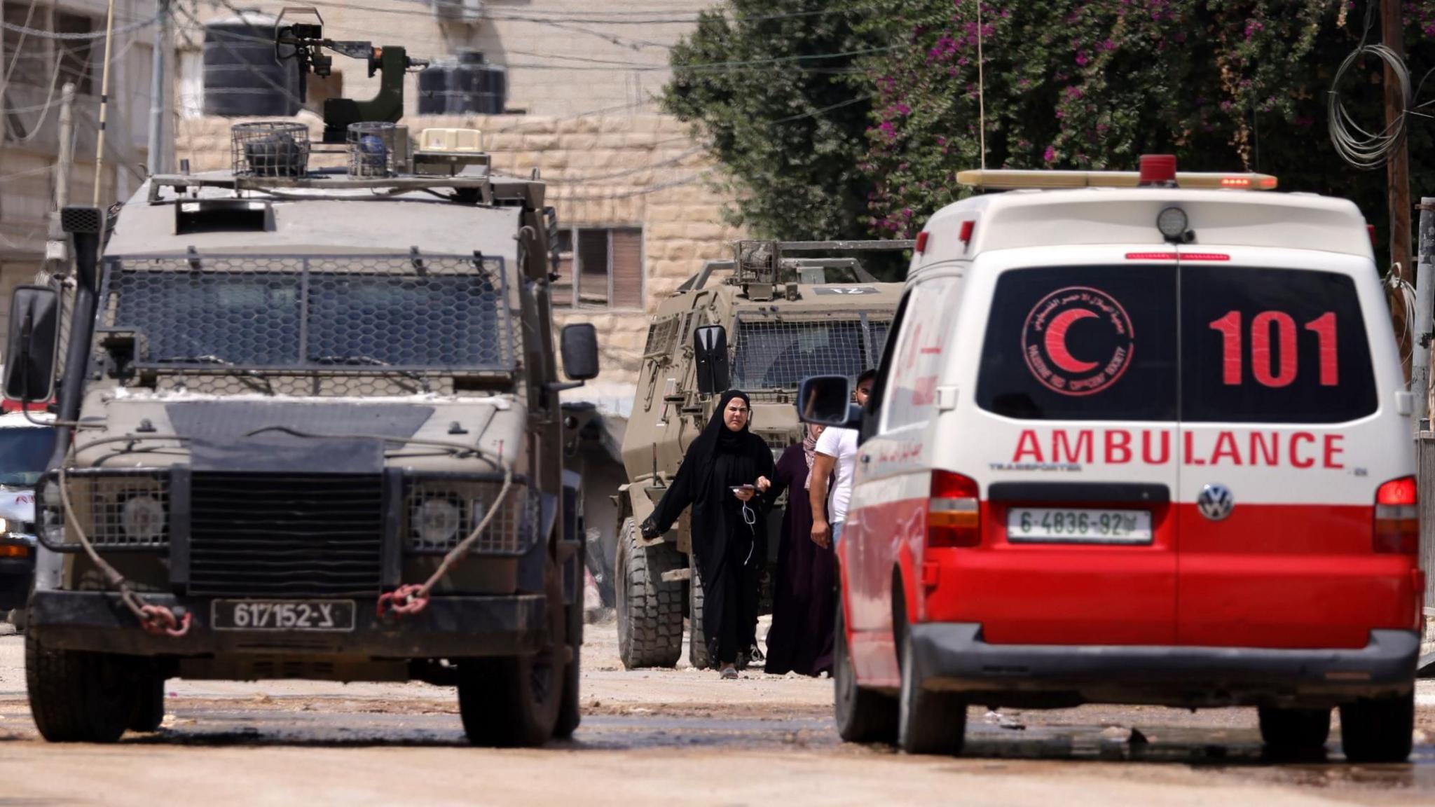 An Israeli military vehicle stops beside a Palestinian Red Crescent ambulance in Jenin, in the occupied West Bank (28 August 2024)