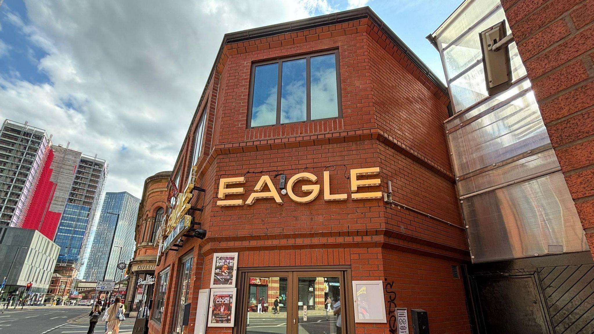A red brick building with brown framed windows and door. Eagle is written on the front in gold letters