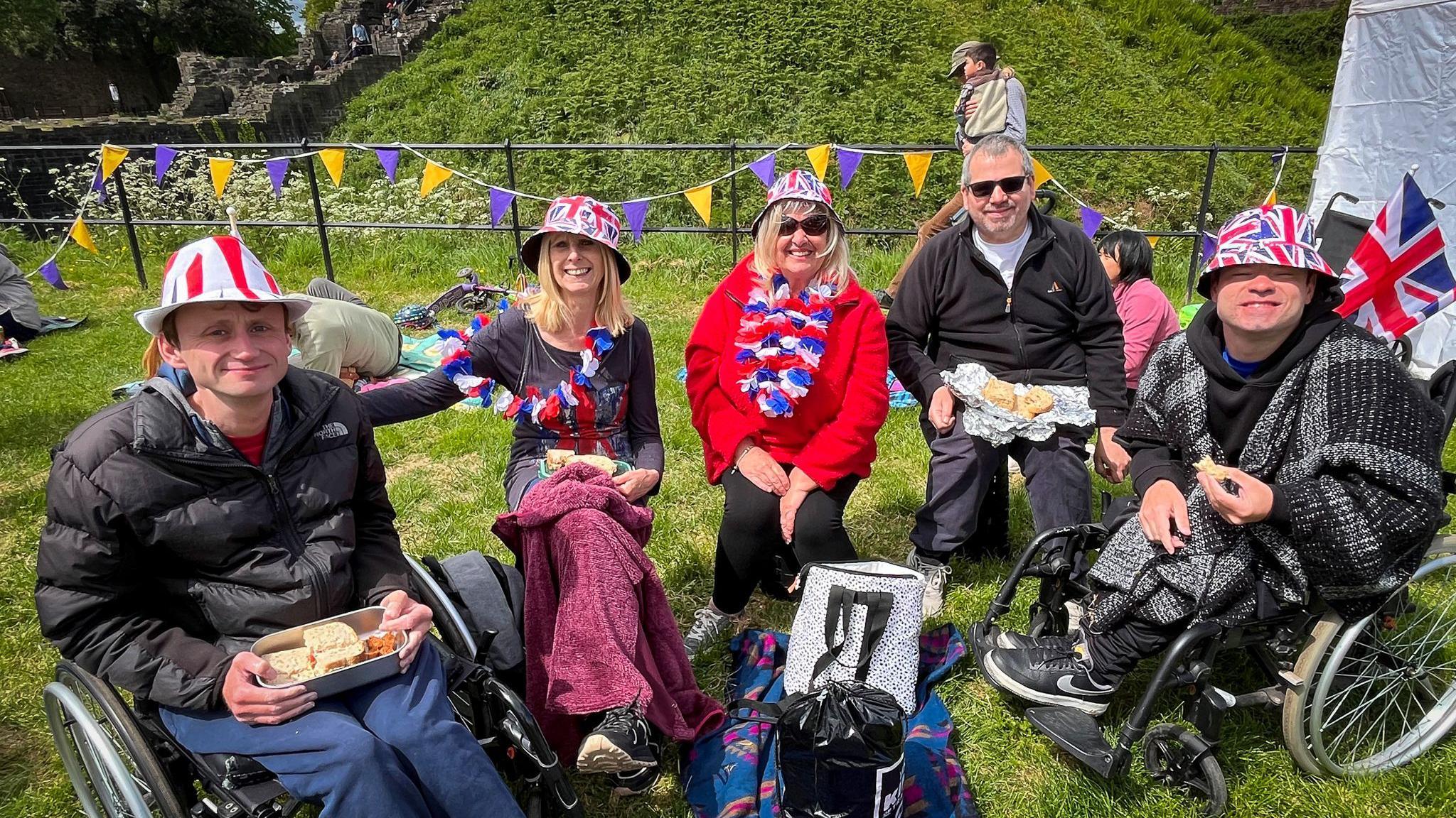 A group of people wearing union jack hats sitting in a field in Cardiff Castle