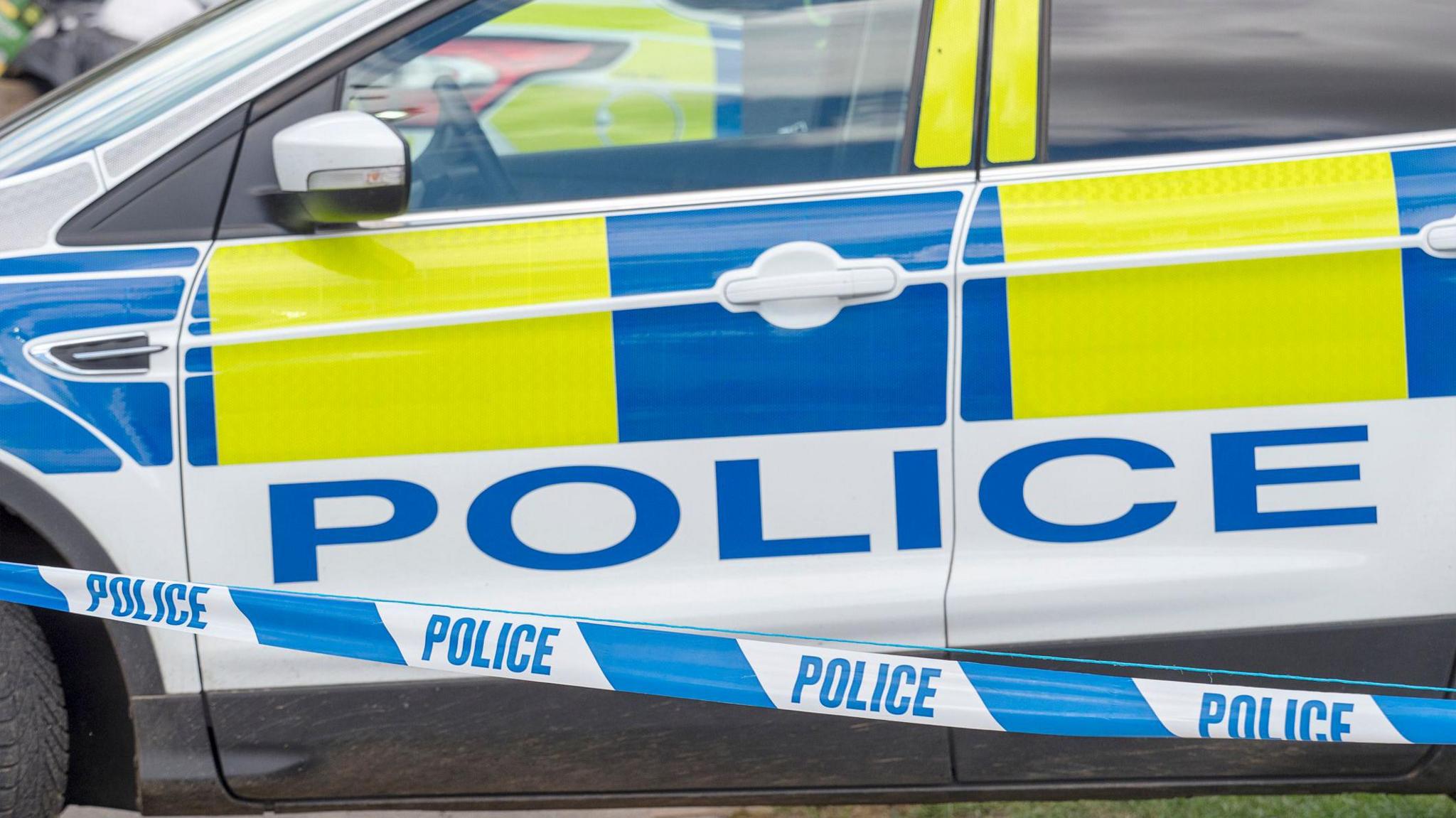 A close-up picture of a police car and police tape 