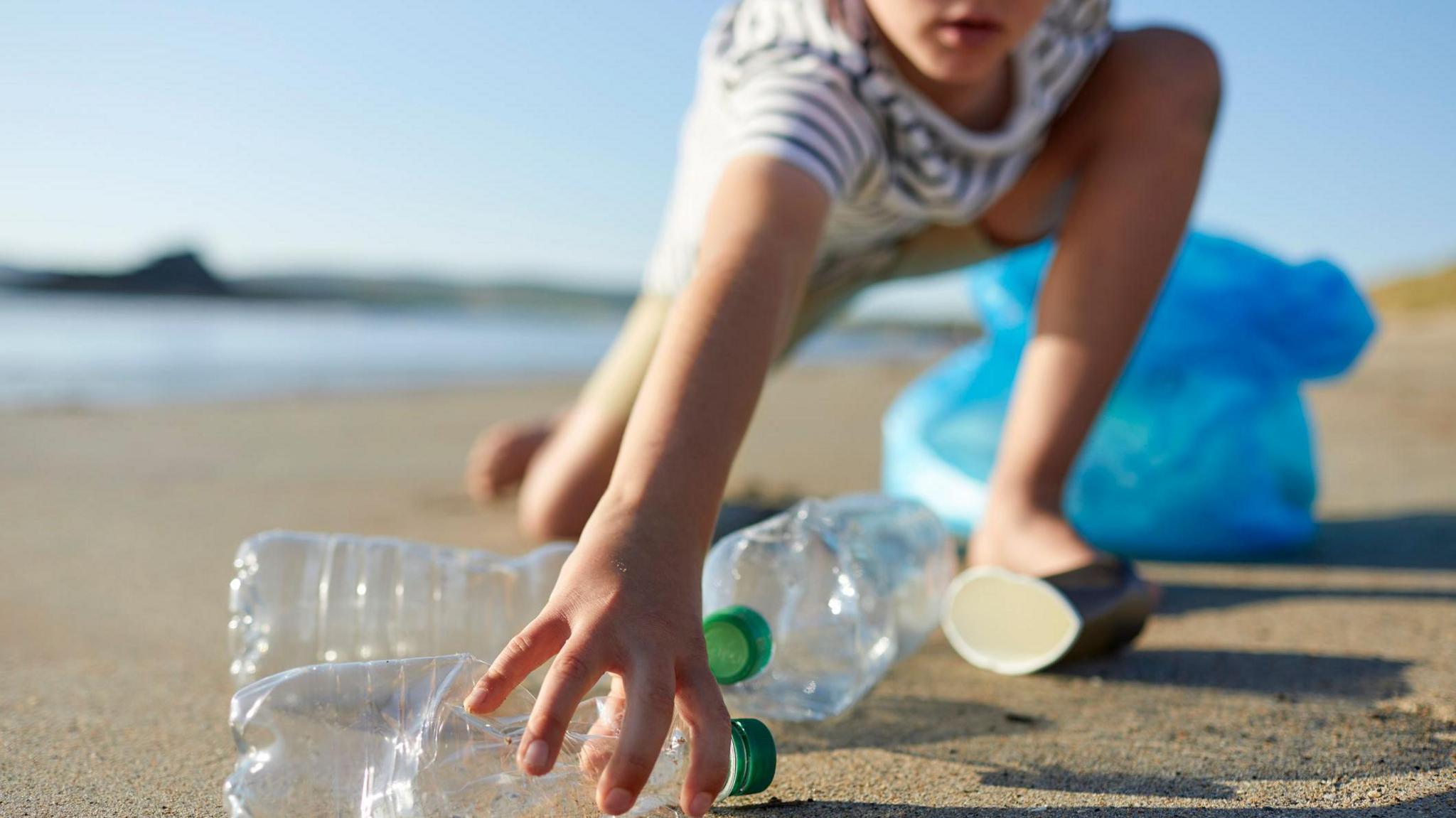 Child picking up plastic bottle