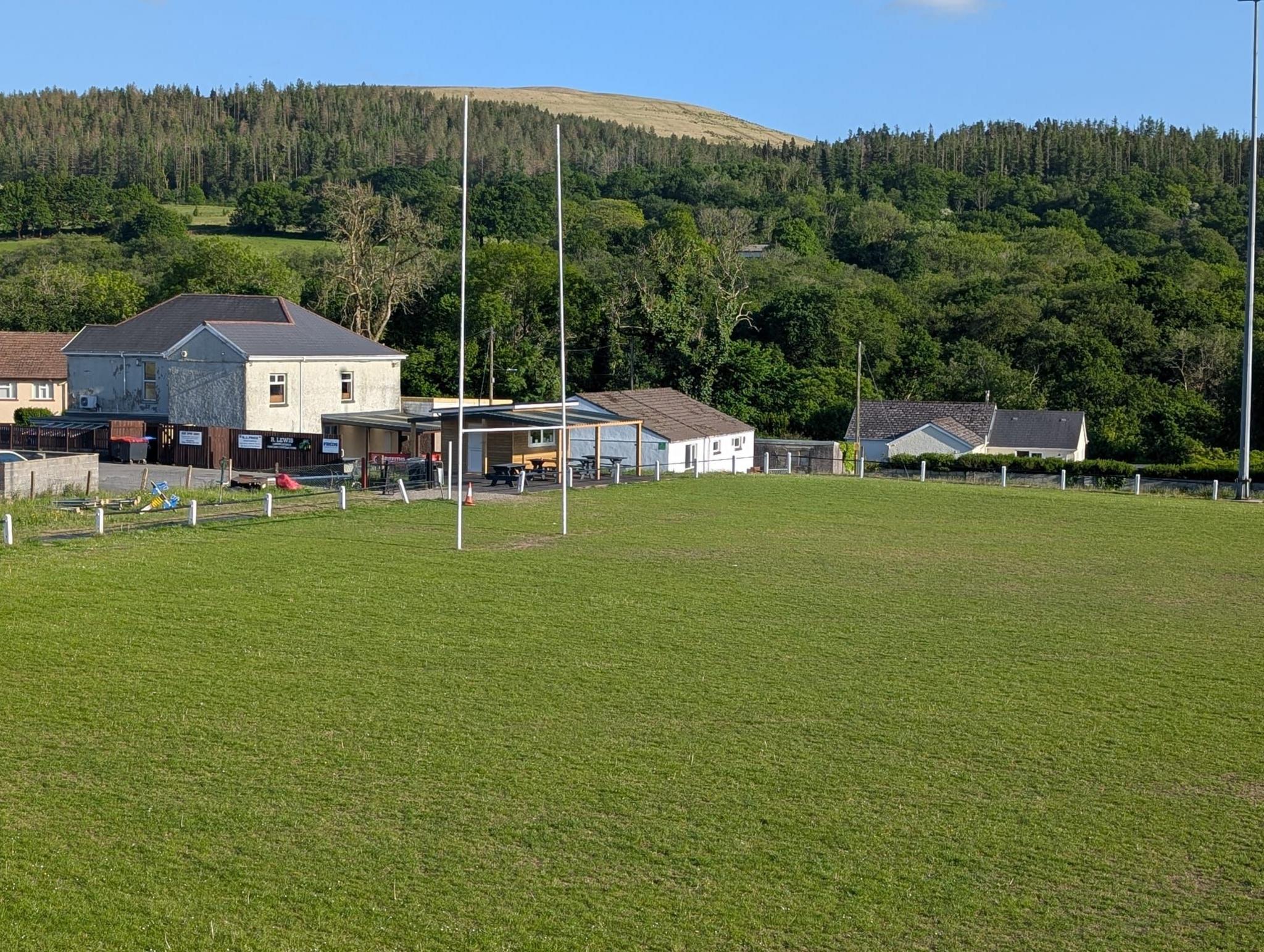 Y cae chwarae gyda chlwb Plas-Y-Ddol yn y cefndir