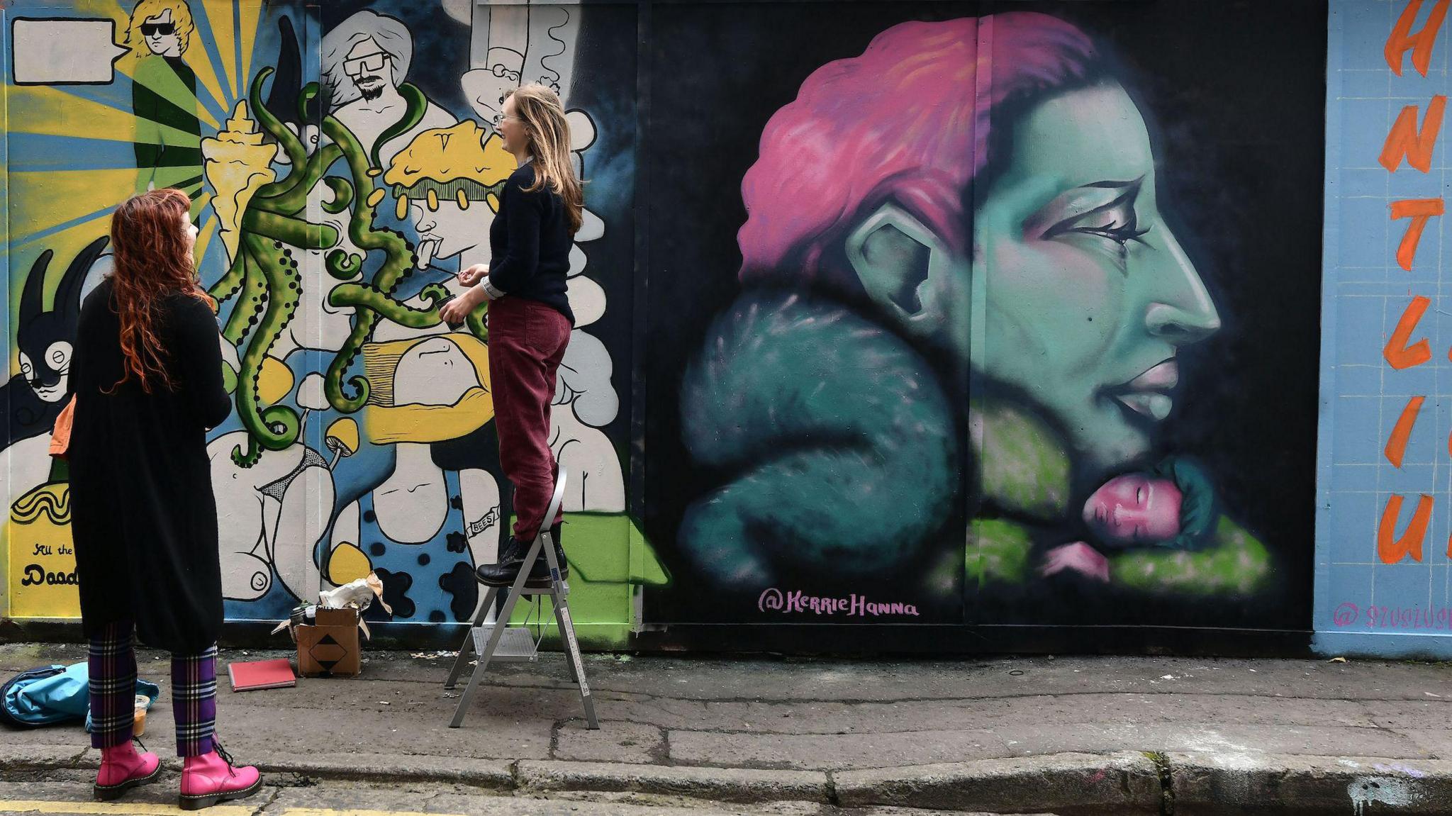 Colourful murals on wall in front of a street.