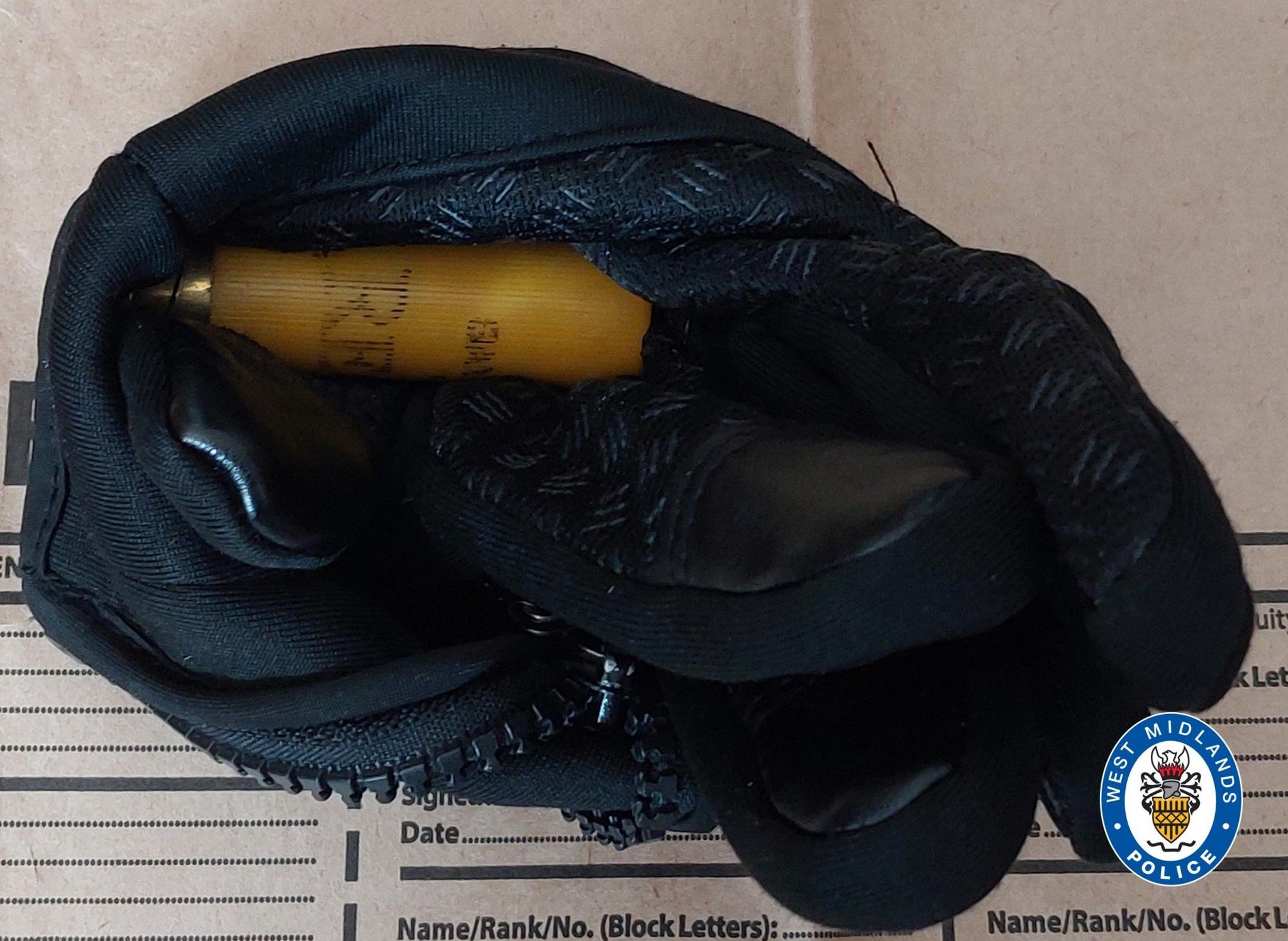 A yellow shotgun cartridge in a black glove with a zip, on top of a white police form.