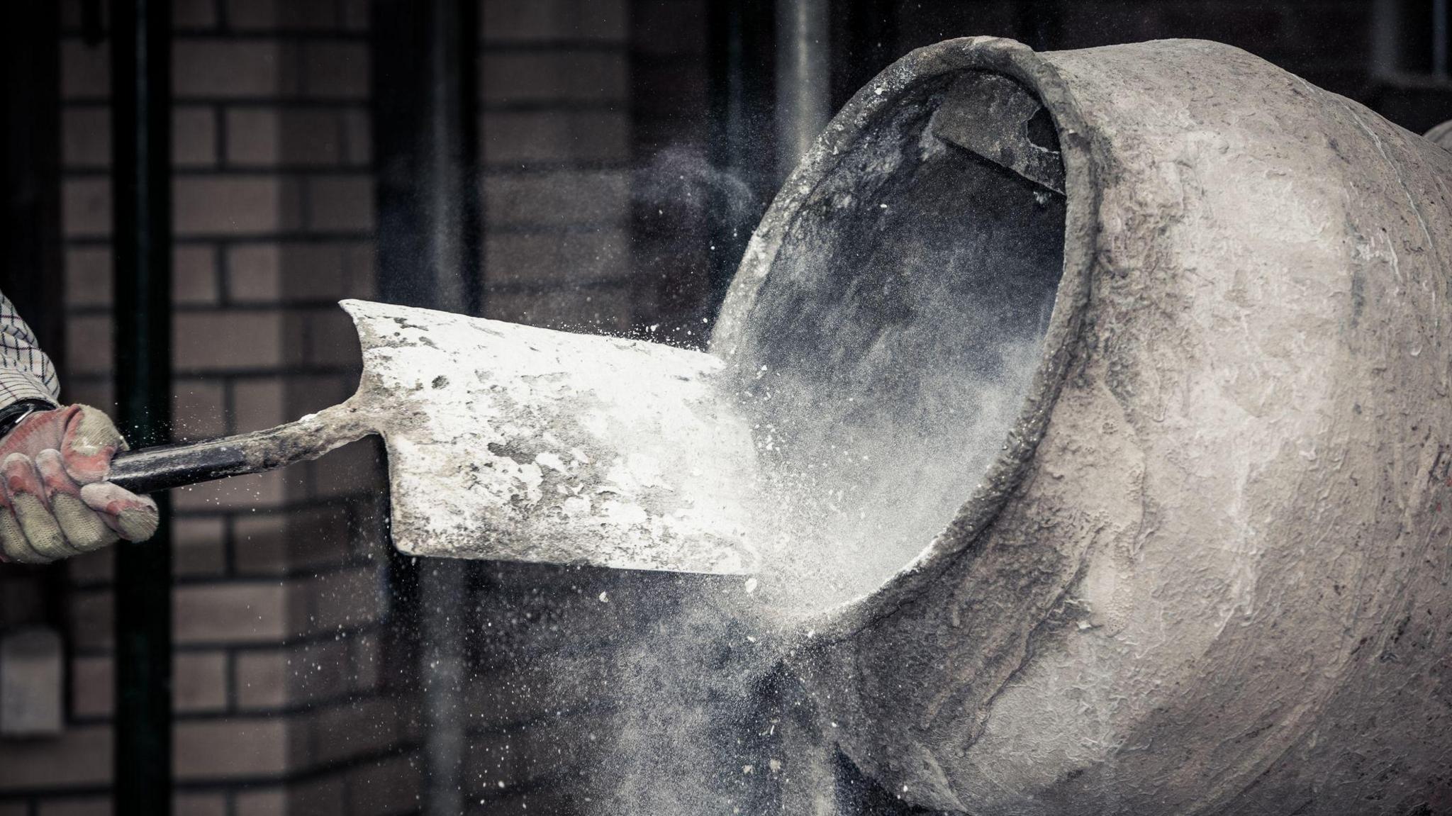 A stock image of dry concrete being shovelled into a cement mixer