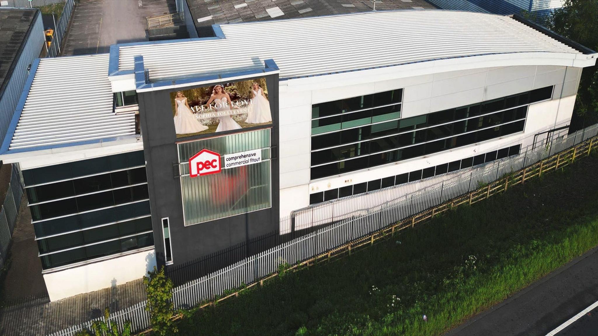 An artist's impression of a digital board on a building off a highway.