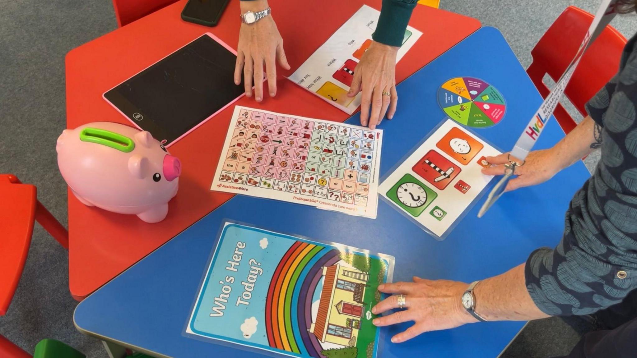 Colourful table with resources including pictorial charts for helping children with speech and language communication needs