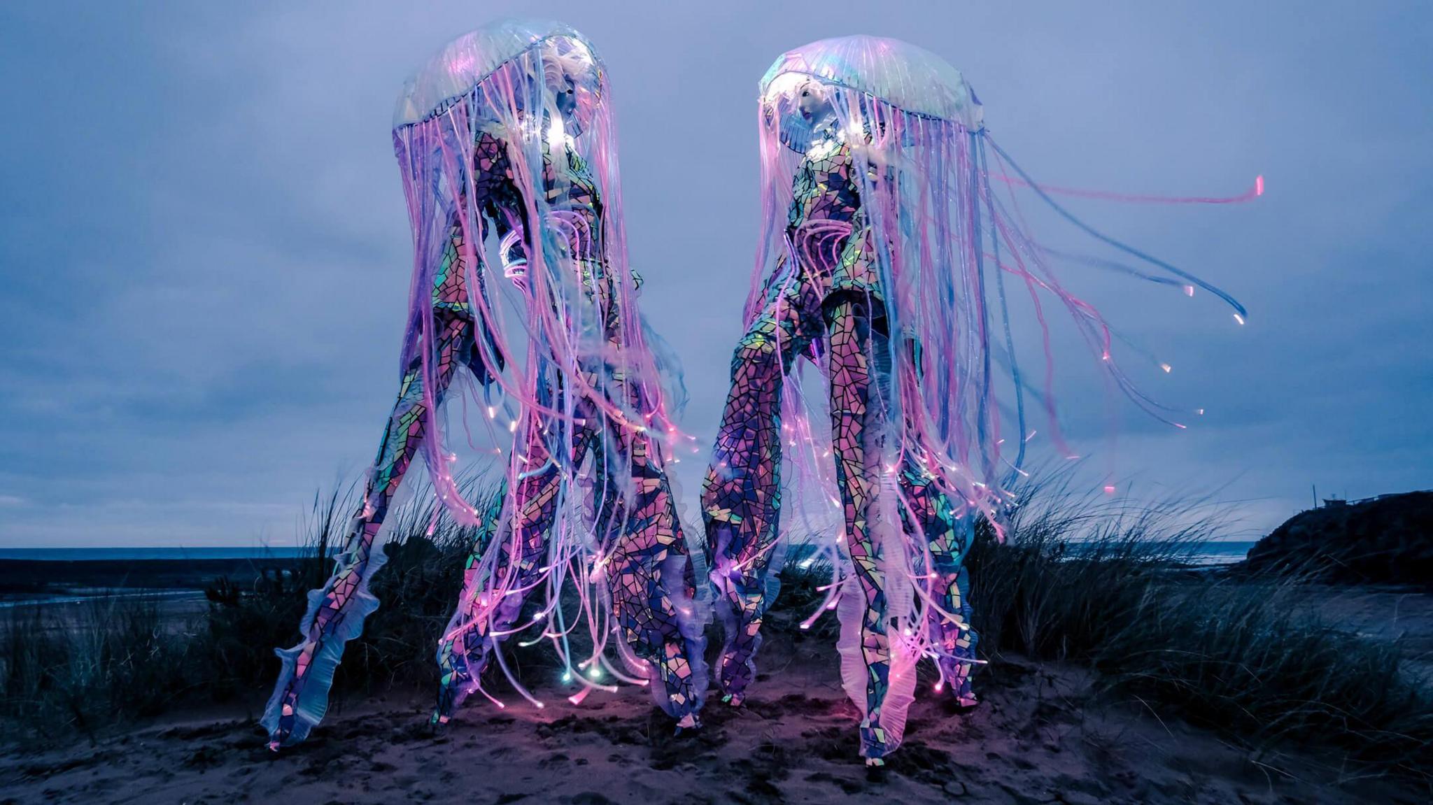 Fluorescent jellyfish art installations of the beach as part of the arts festival. It's dark and stormy.