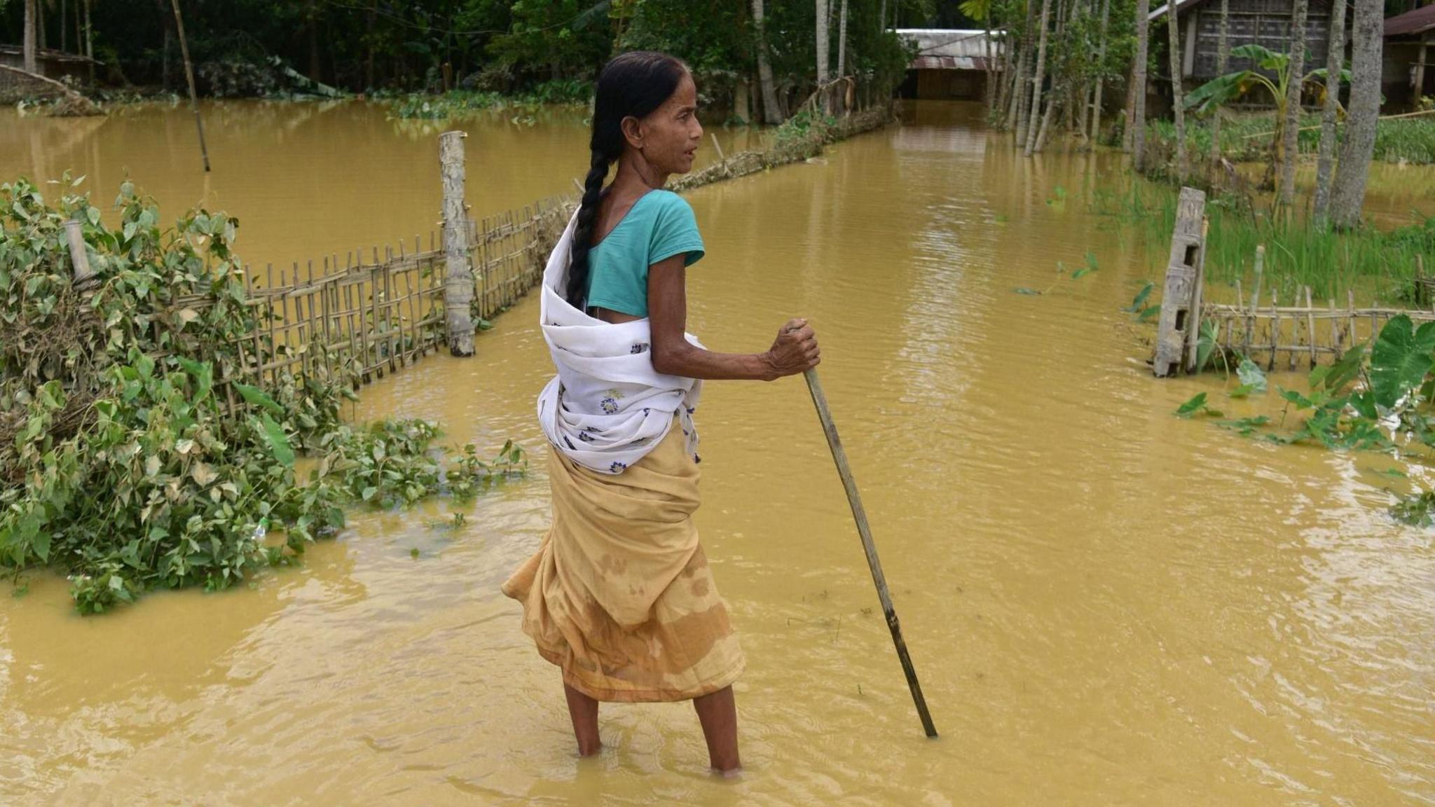 A villager wades through floodwaters after heavy rains in Teok, in the Jorhat district of Assam state, India, 21 July 2026.
