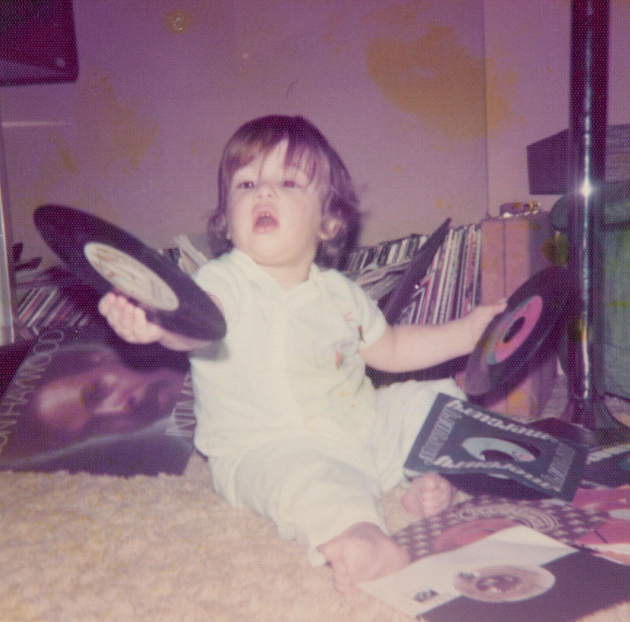 Mark Ronson as a toddler, holding up several 7-inch singles