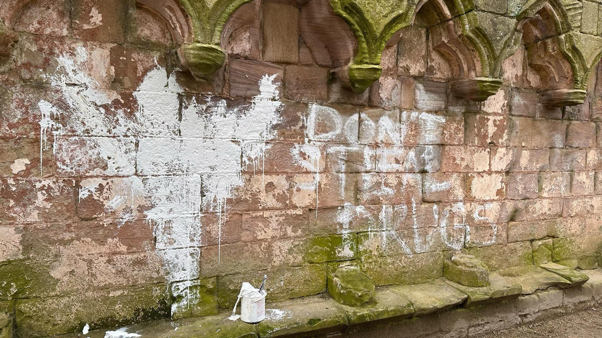 White paint spells out "Don't steal drugs" on a medieval abbey.