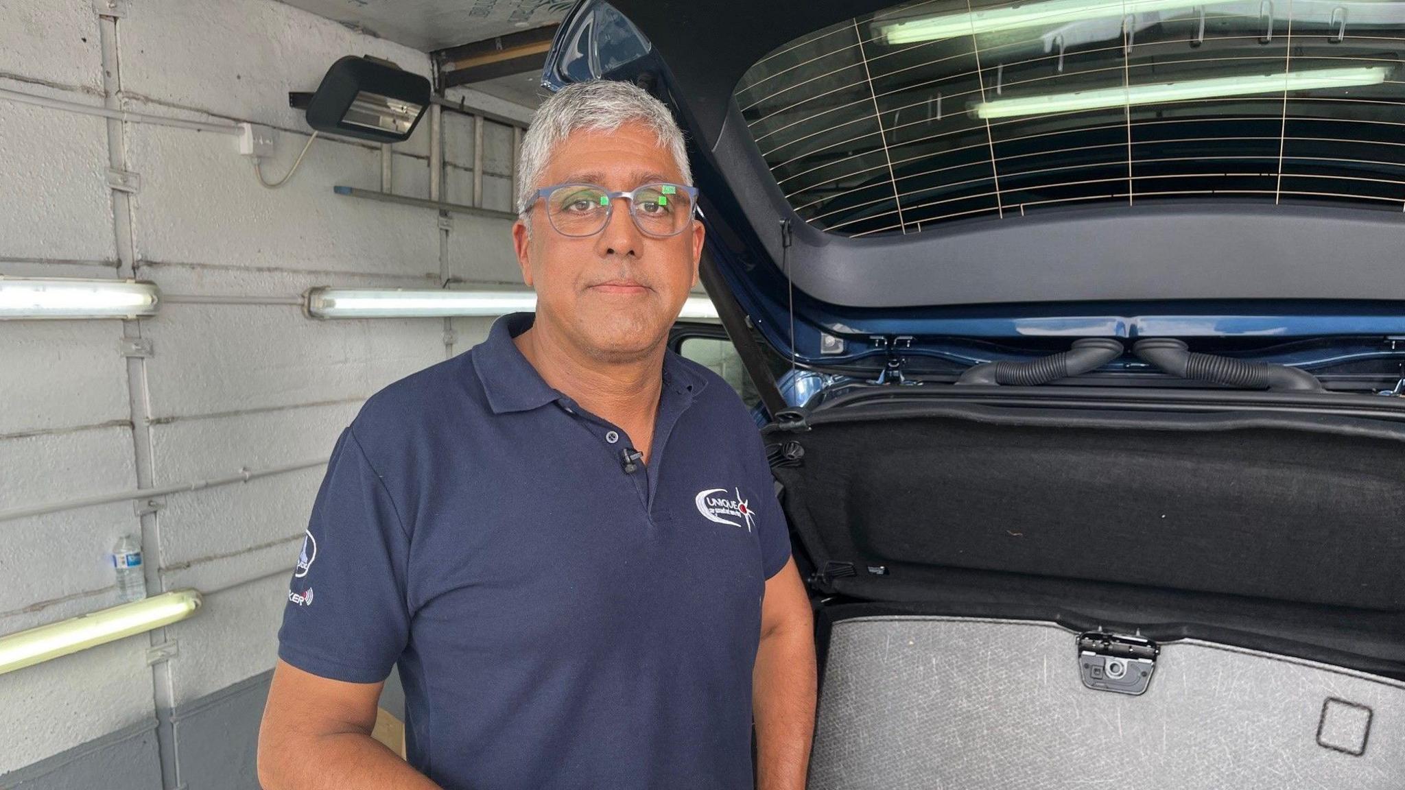 Richard Almeida in his workshop with the boot of a car open