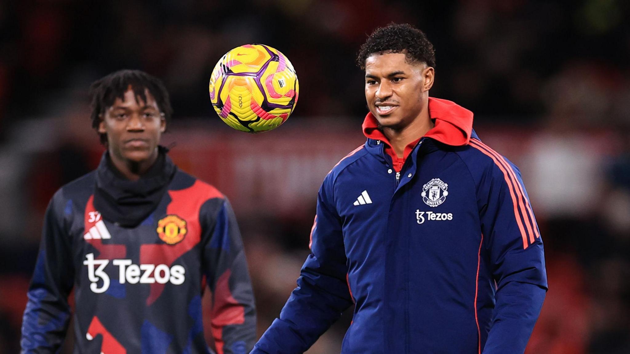 Marcus Rashford warms up with ball while Kobbie Mainoo looks on