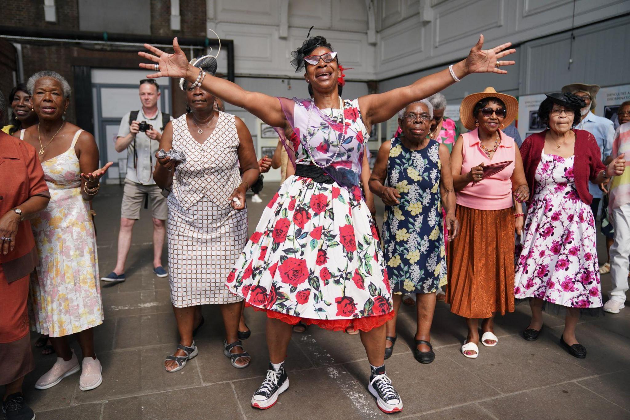 Women in colourful dresses dance at a reception following the arrival of a Thames Clipper at the Port Of Tilbury with 100 NHS workers and 100 people with Windrush connections to mark the 75th anniversary of the arrival of the Empire Windrush. Picture date: Thursday June 22, 2023.