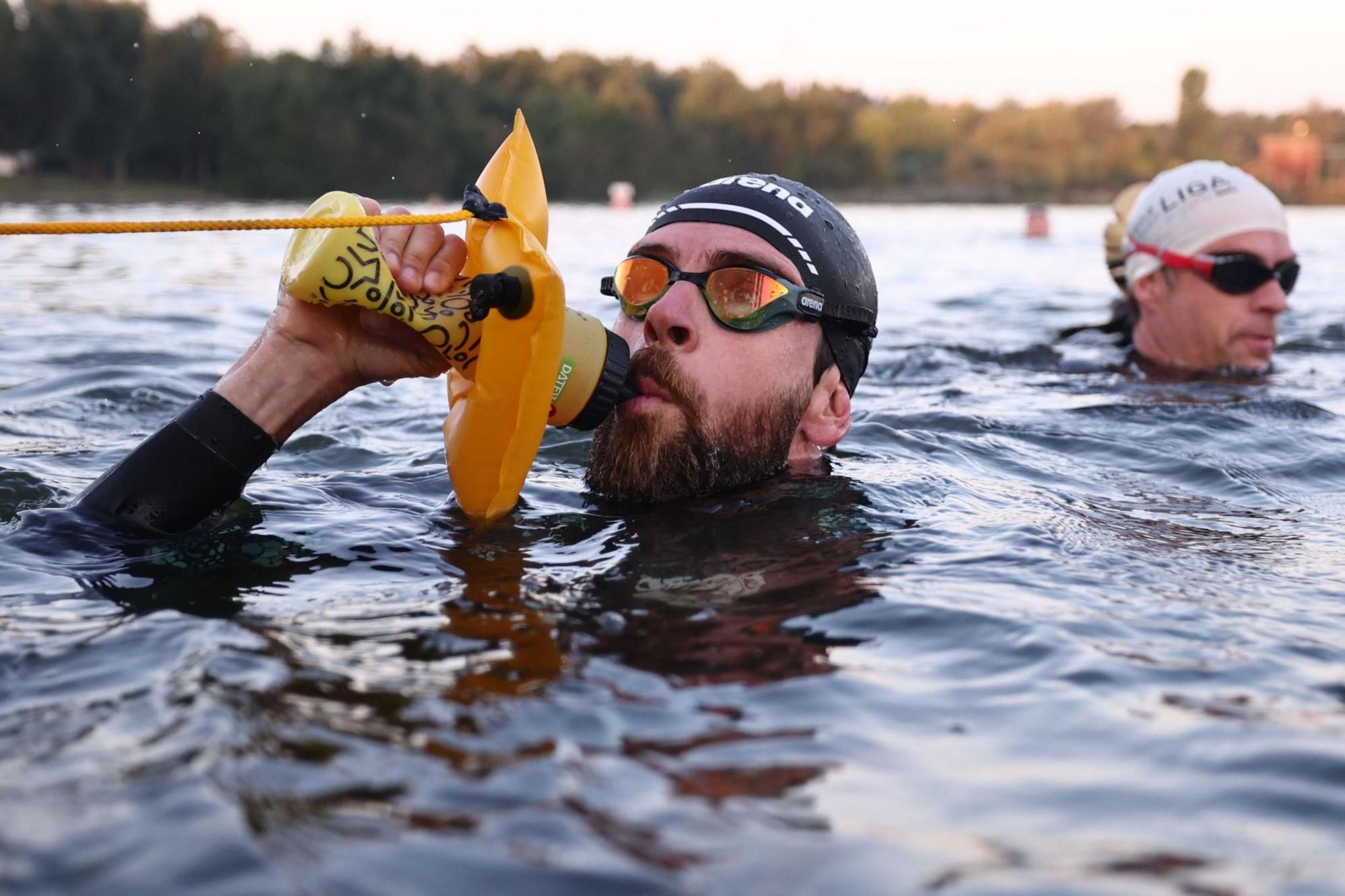 Extreme athlete Jonas Deichmann drinks as he swims across a lake in Roth, Germany