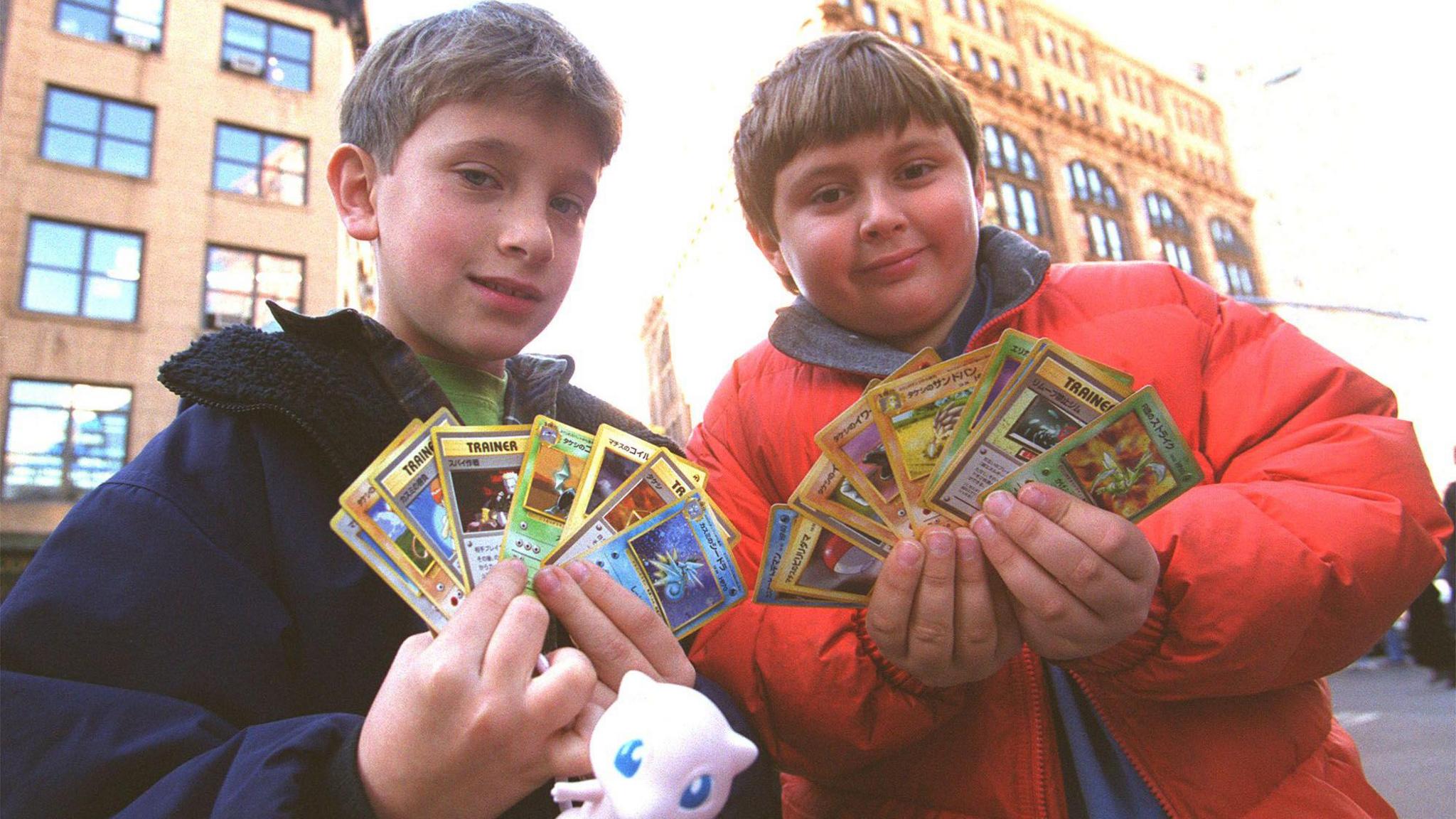 Two children showing off their Pokémon cards