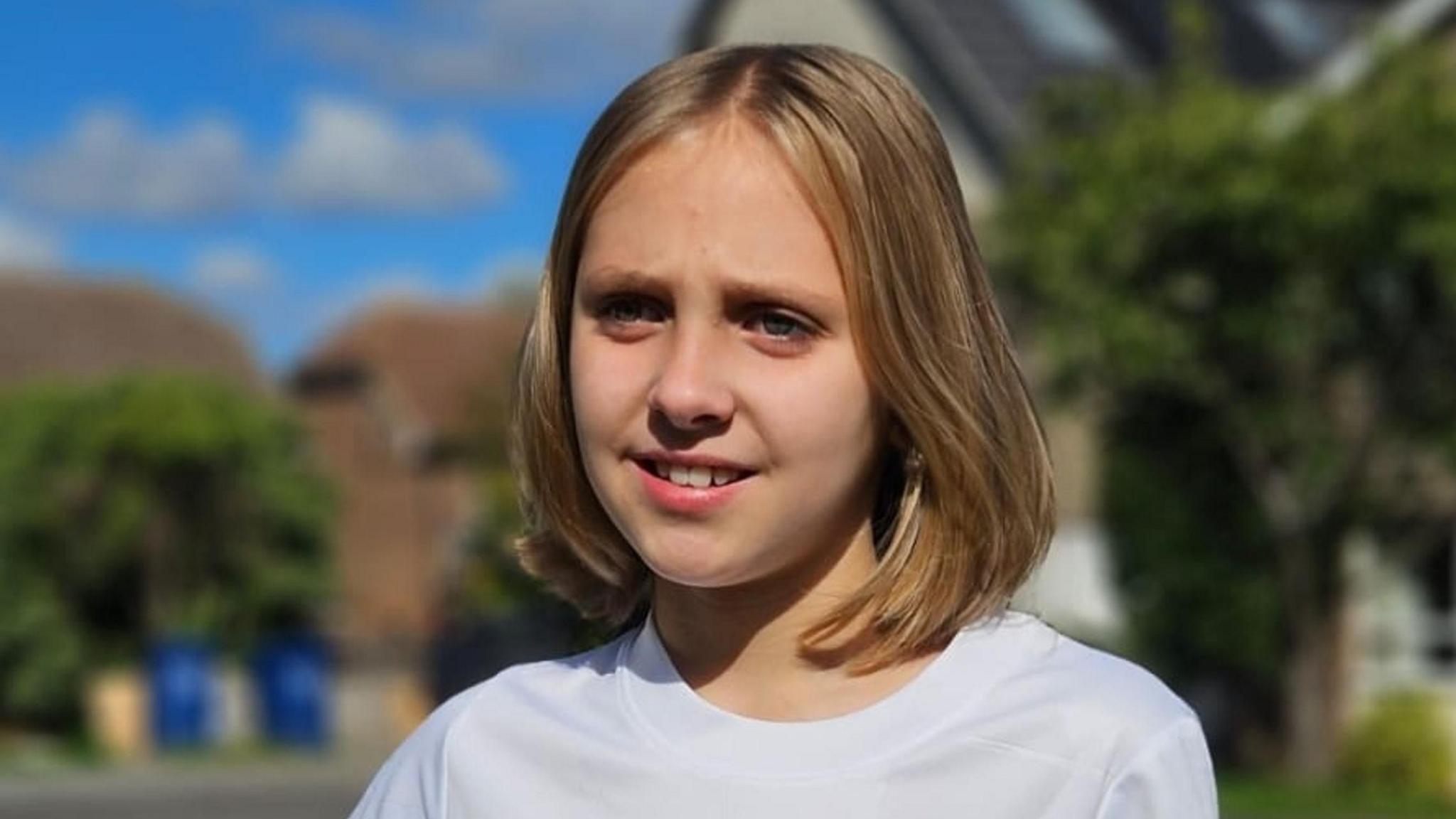 Caitlin Passey with long brown hair wearing a white top