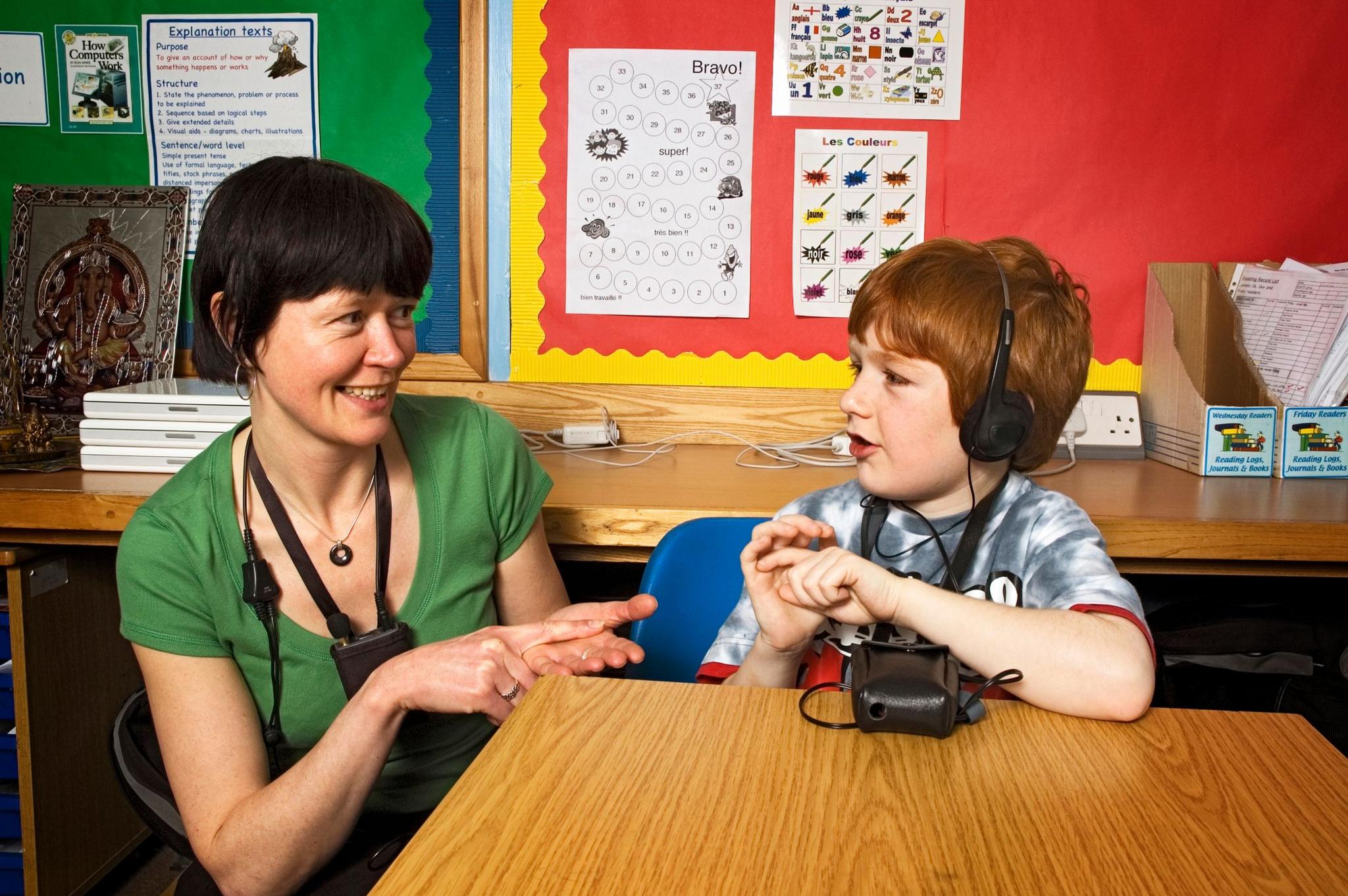 Deaf school boy aged seven years and his teacher using sign language in a school class room 