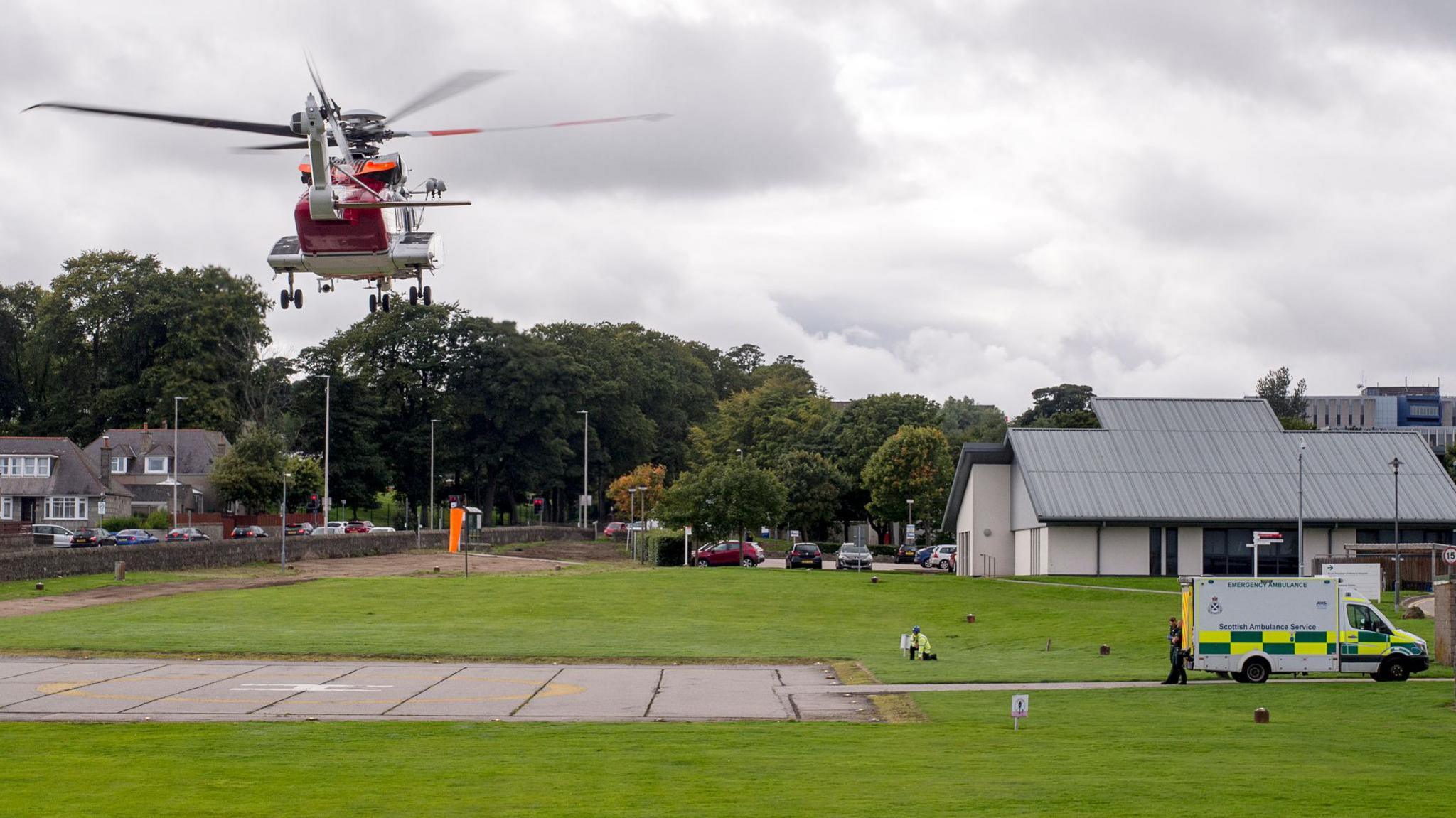 A coastguard helicopter landing at Aberdeen Royal Infirmary. An ambulance is parked near the landing site