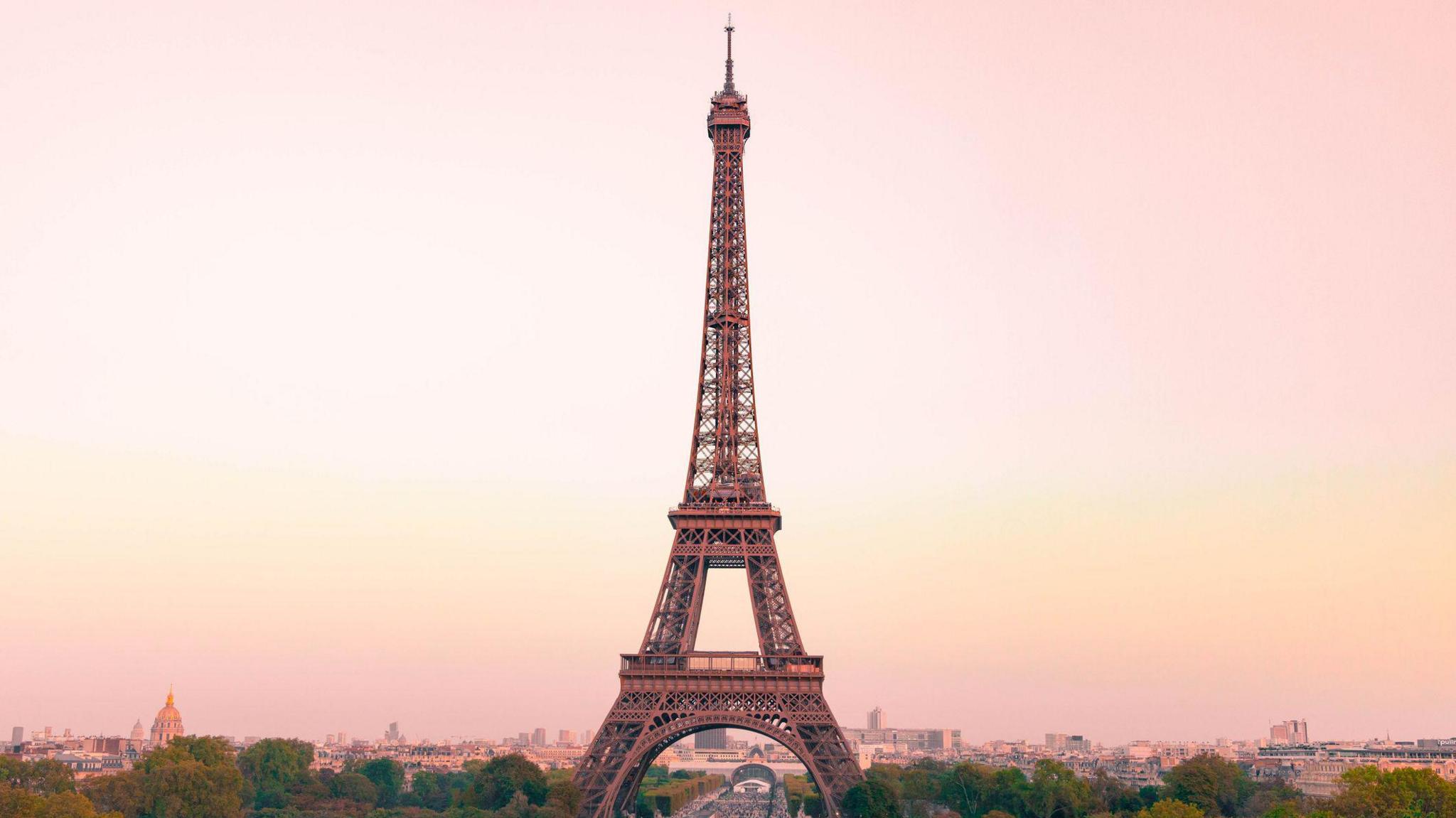the Eiffel Tower against a pink and yellow sunset sky
