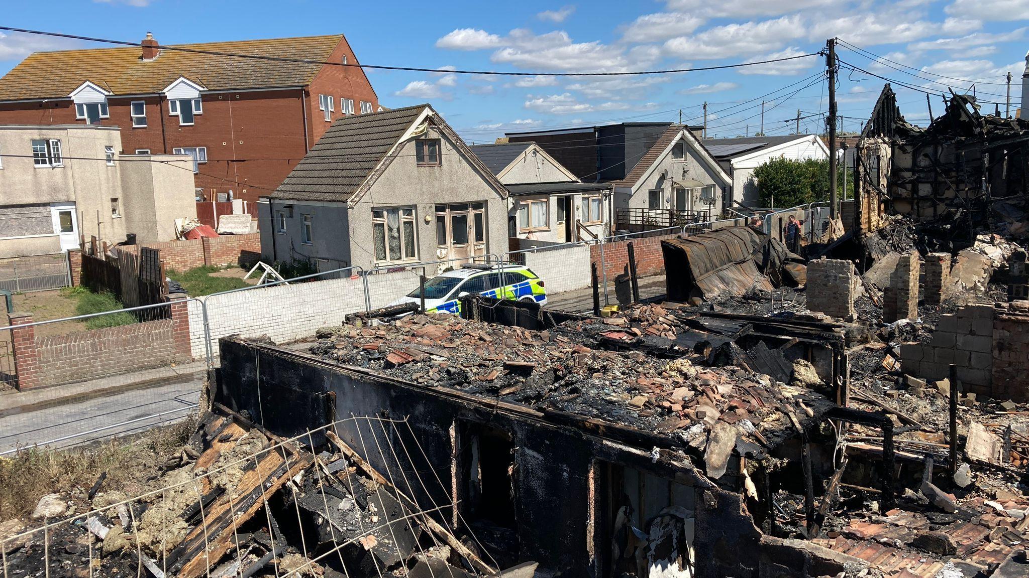 A row of destroyed houses in Jaywick with a police car in the background