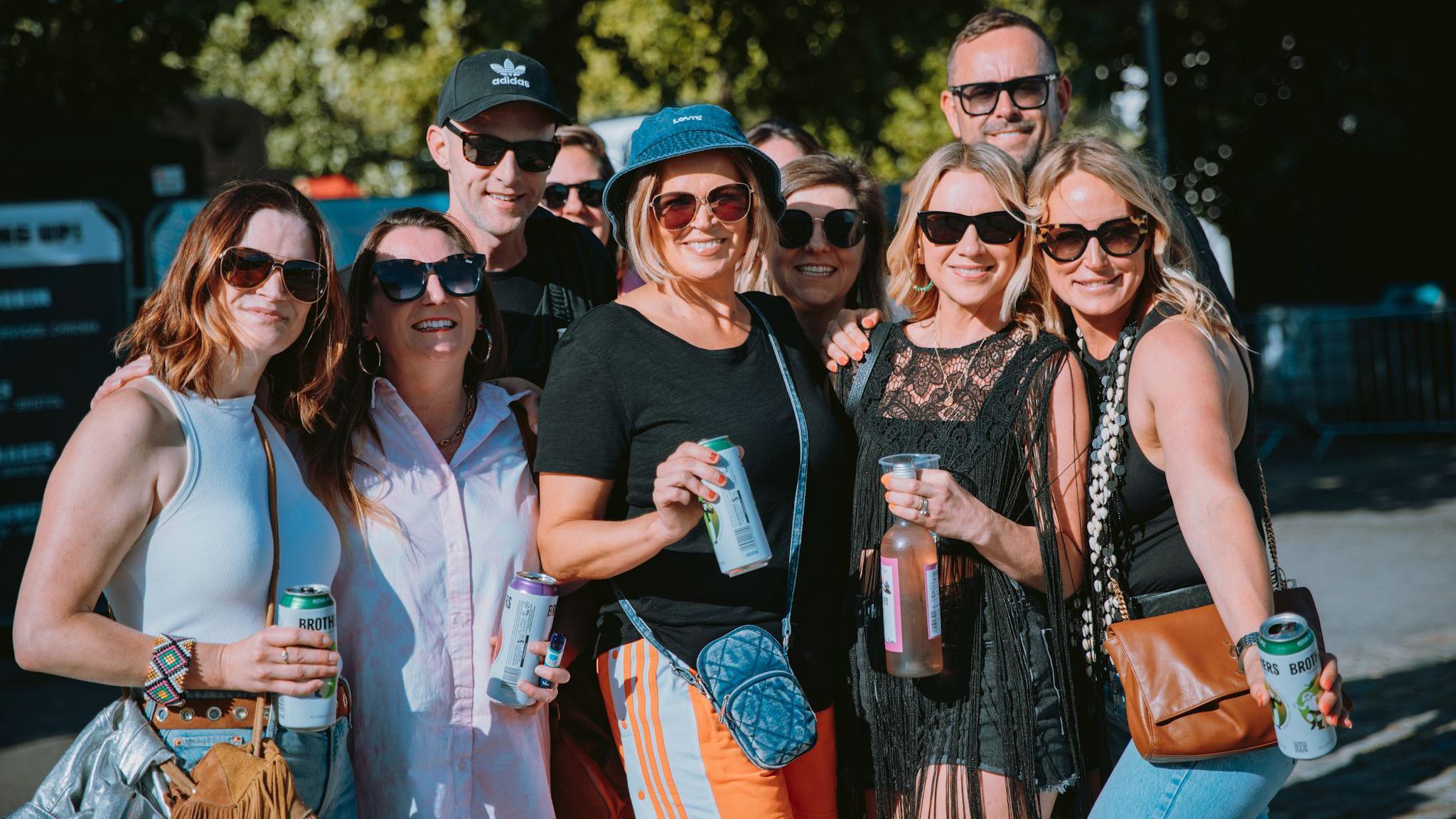 A group of people holding drinks smile at the camera ahead of the Annie Mac concert at Bristol Sounds 2024