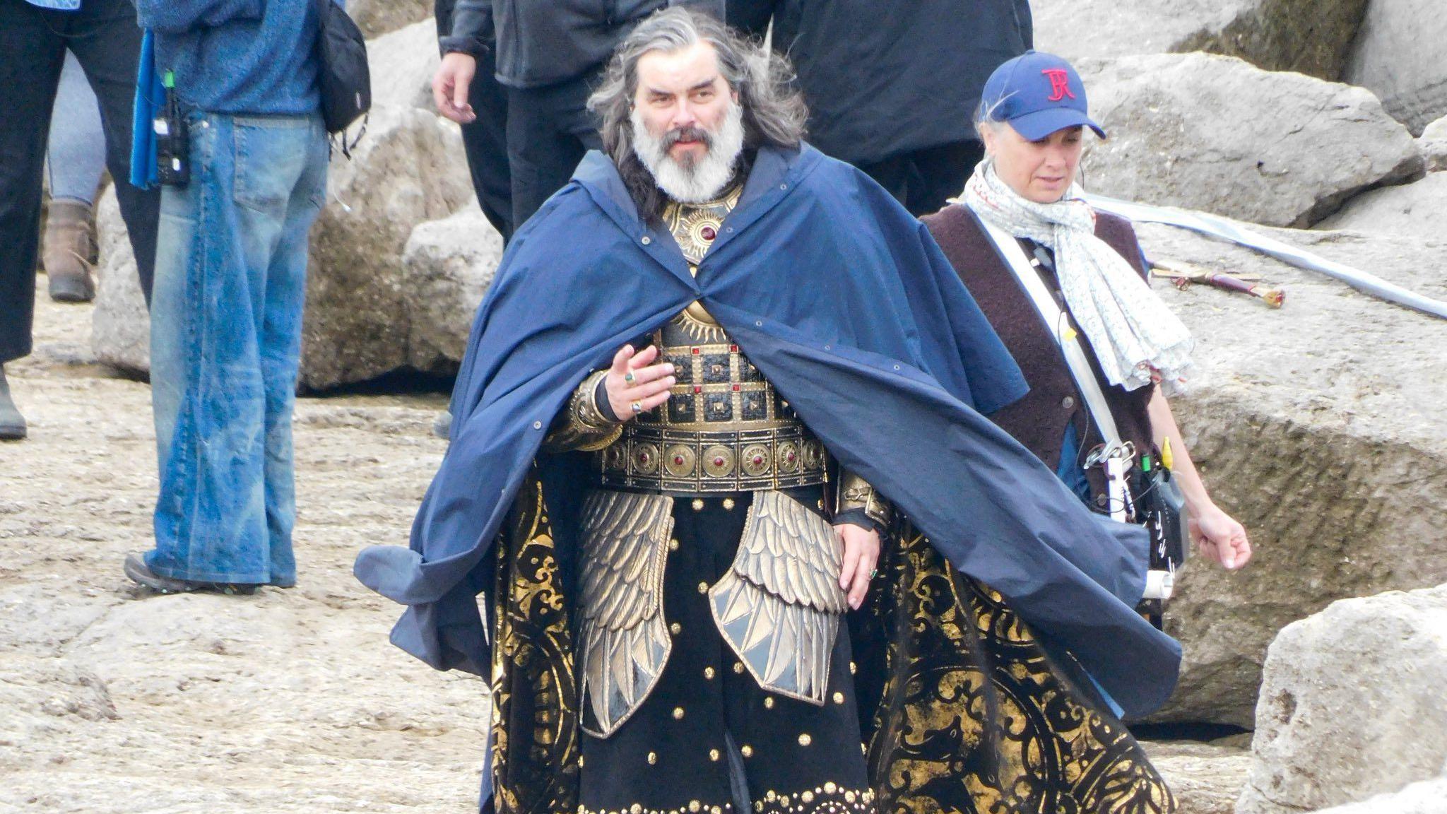Trystan Gravelle as Pharazôn at the shooting day at Pulpit Rock. He is pointing to something off screen with his right hand. Other actors and filming crews could be seen behind him.