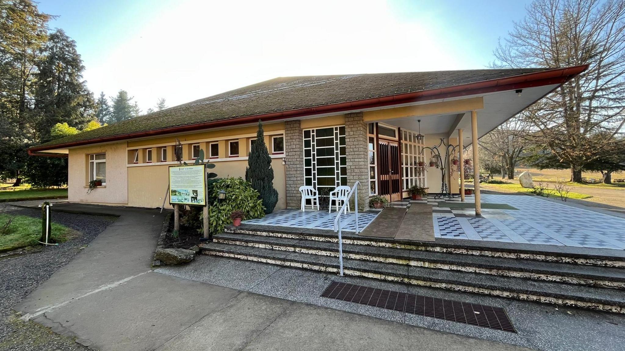 A single-story building with a porch and small windows. 
