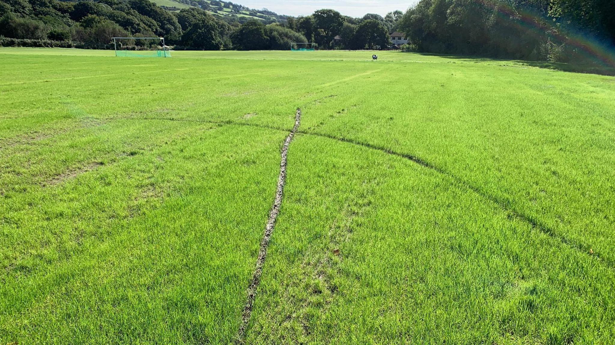 Football pitch with deep tyre tracks running through it