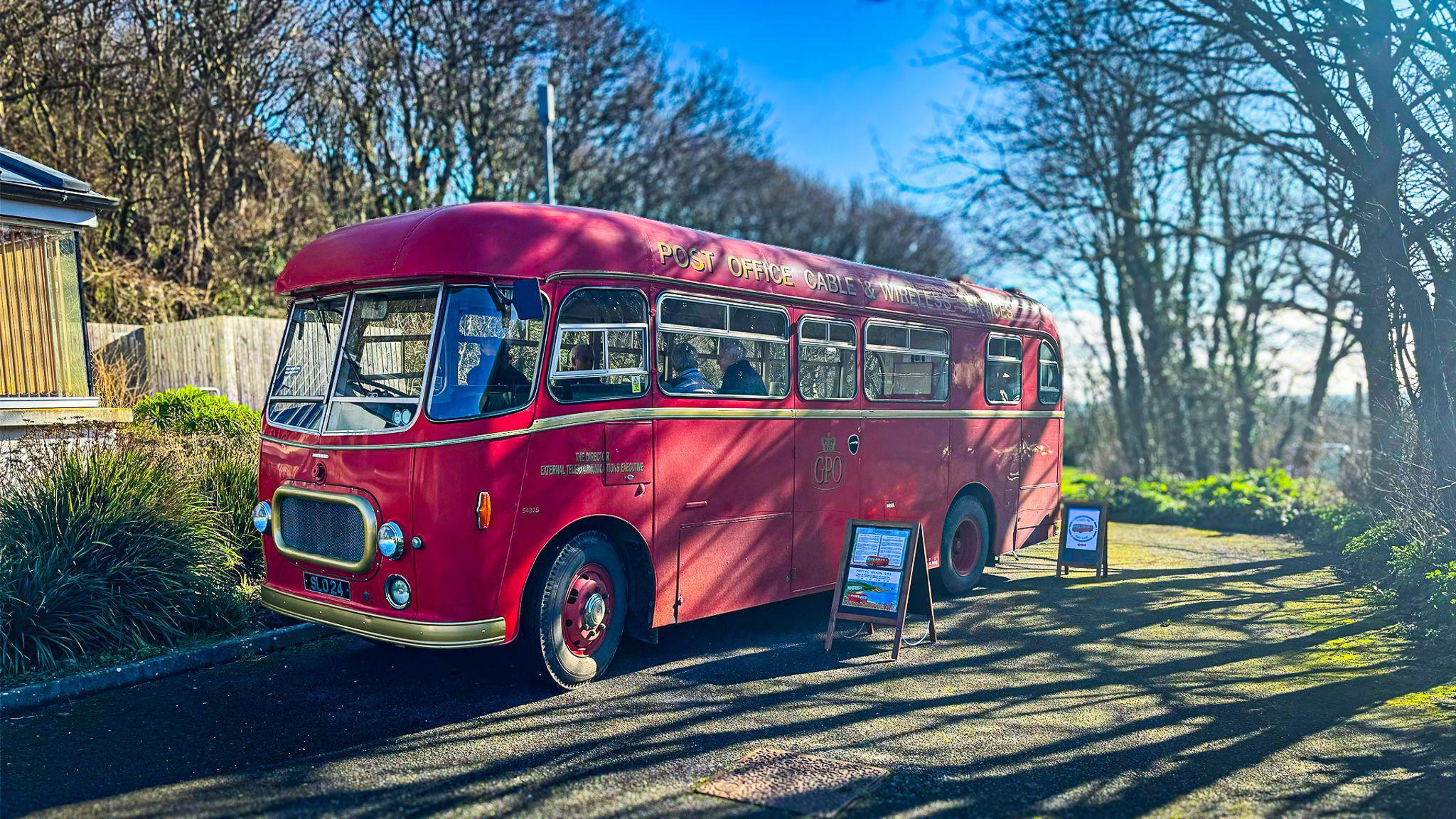 A red 1950s bus with gold bumpers and trim. 