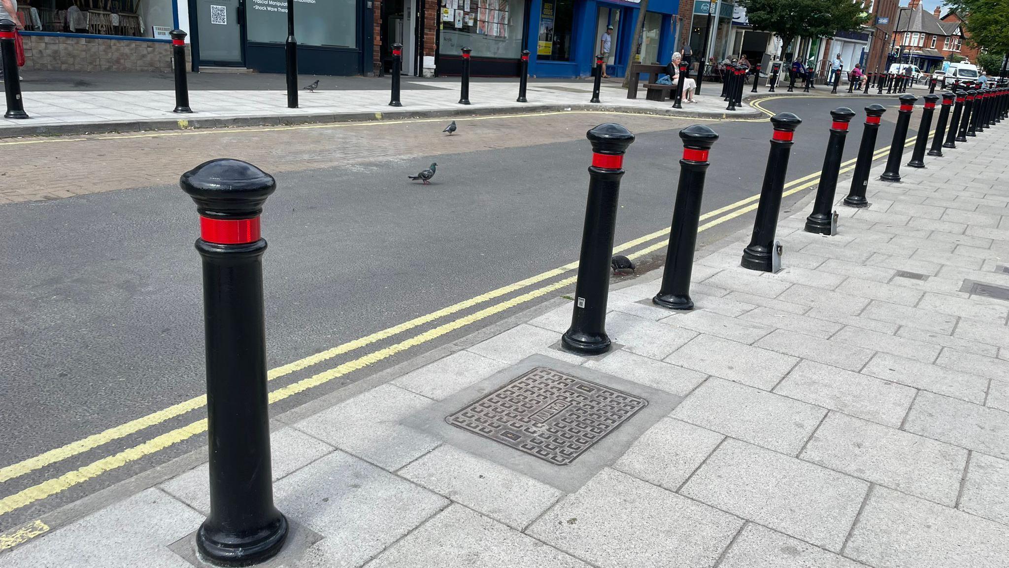 The black bollards lining Acomb Front Street with shops in the background.