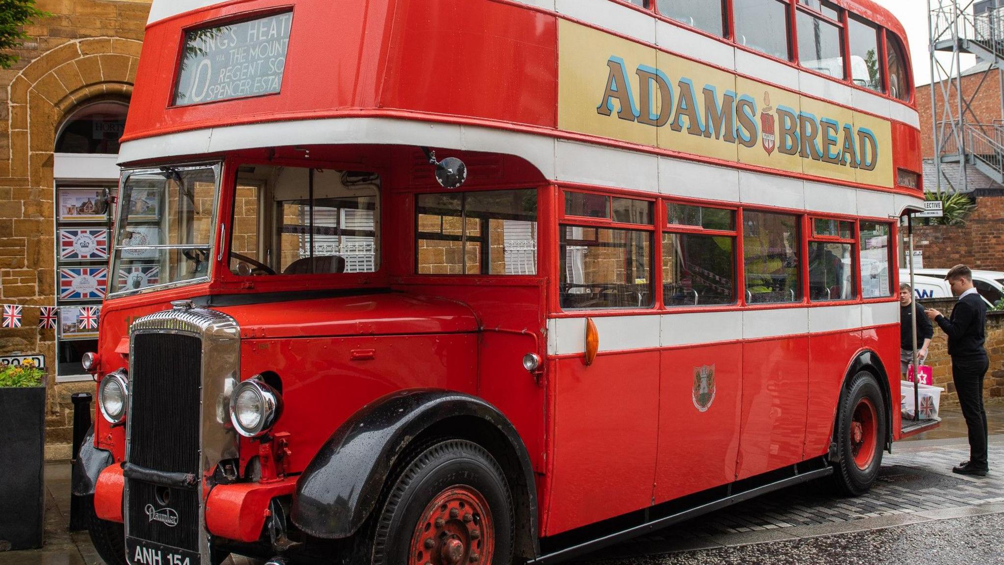 A number 10 red double decker bus with "Adams Bread" written as an advert on the side. 