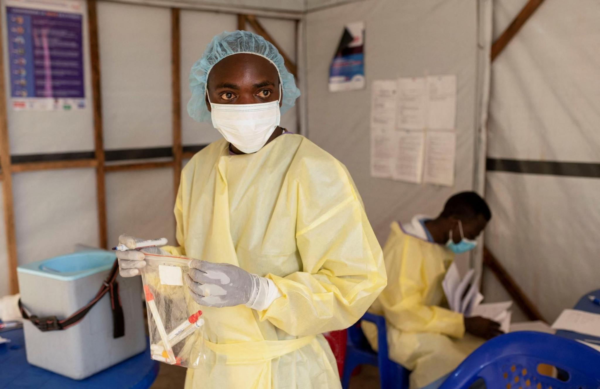 Christian Musema, a laboratory nurse wearing a mask, hairnet, gloves and a yellow protective gown, handles samples taken from a child suspected of having mpox near Goma in DR Congo on 19 July, 2024. 