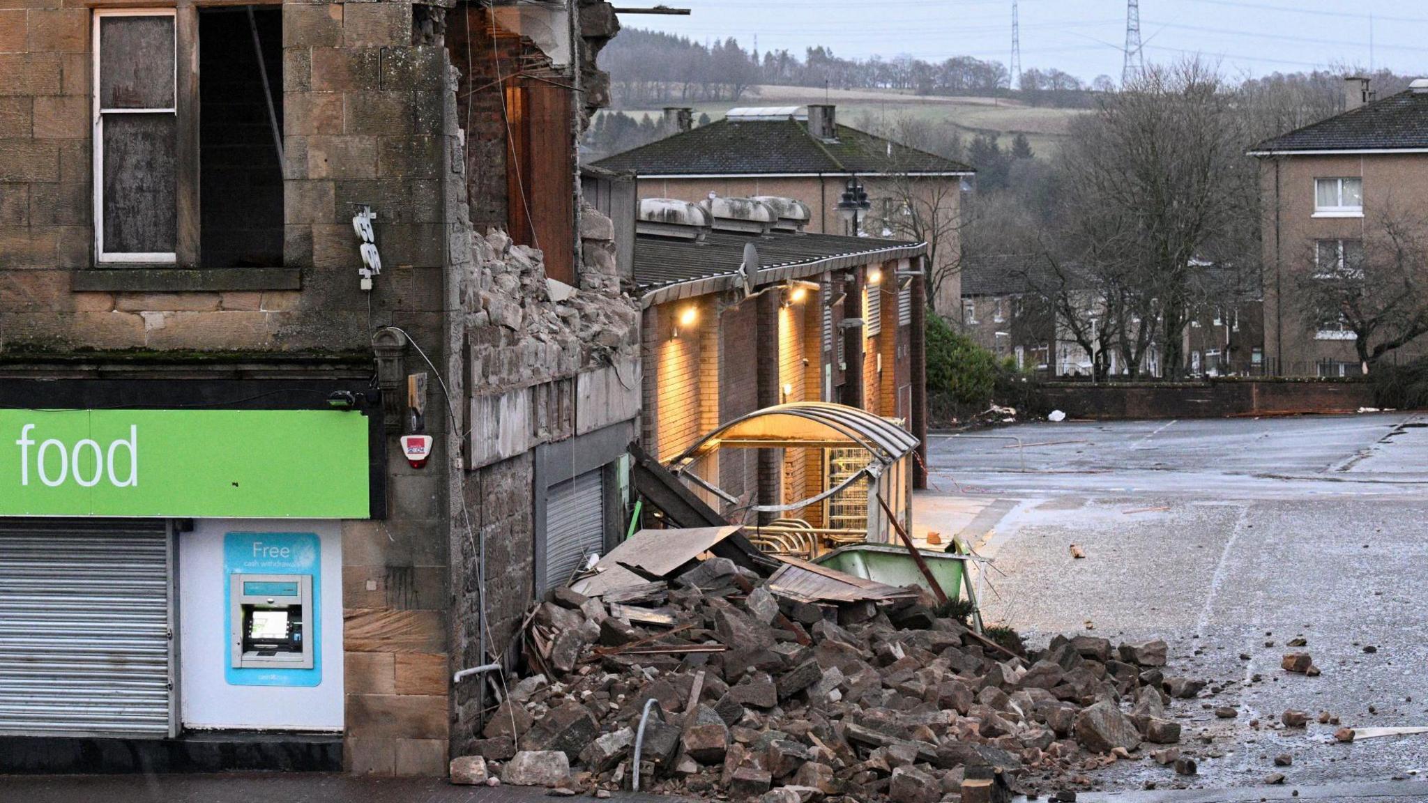 A large pile of rubble and debris on a pavement from a flat above a shop with a collapsed wall - the entire side of the building is missing. Taken on Friday in the town of Denny near Falkirk.