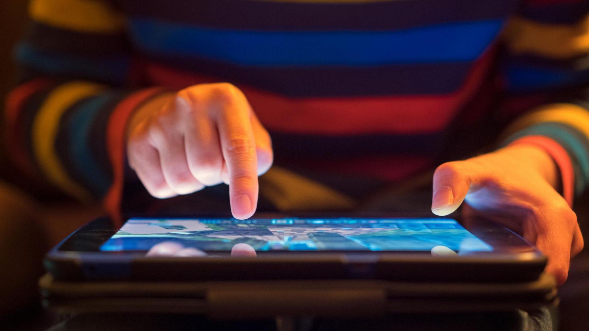 Man in striped jumper holding iPad