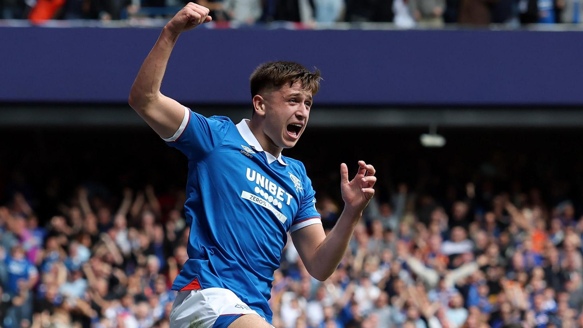 Mikey Moore of Rangers celebrates with a raised clenched hand in front of a large crowd