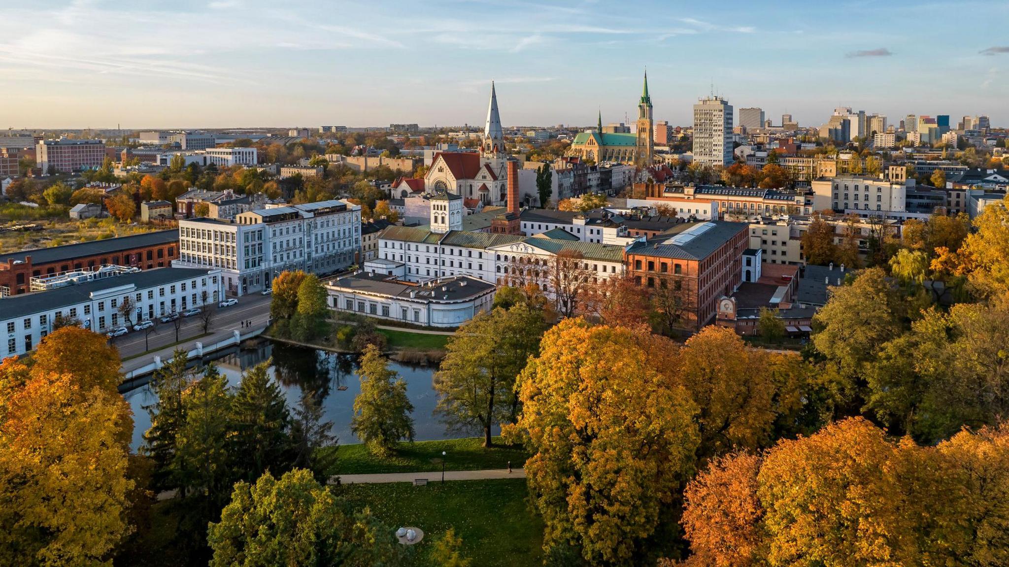 Aerial view of pretty trees, a pond and buildings beyond