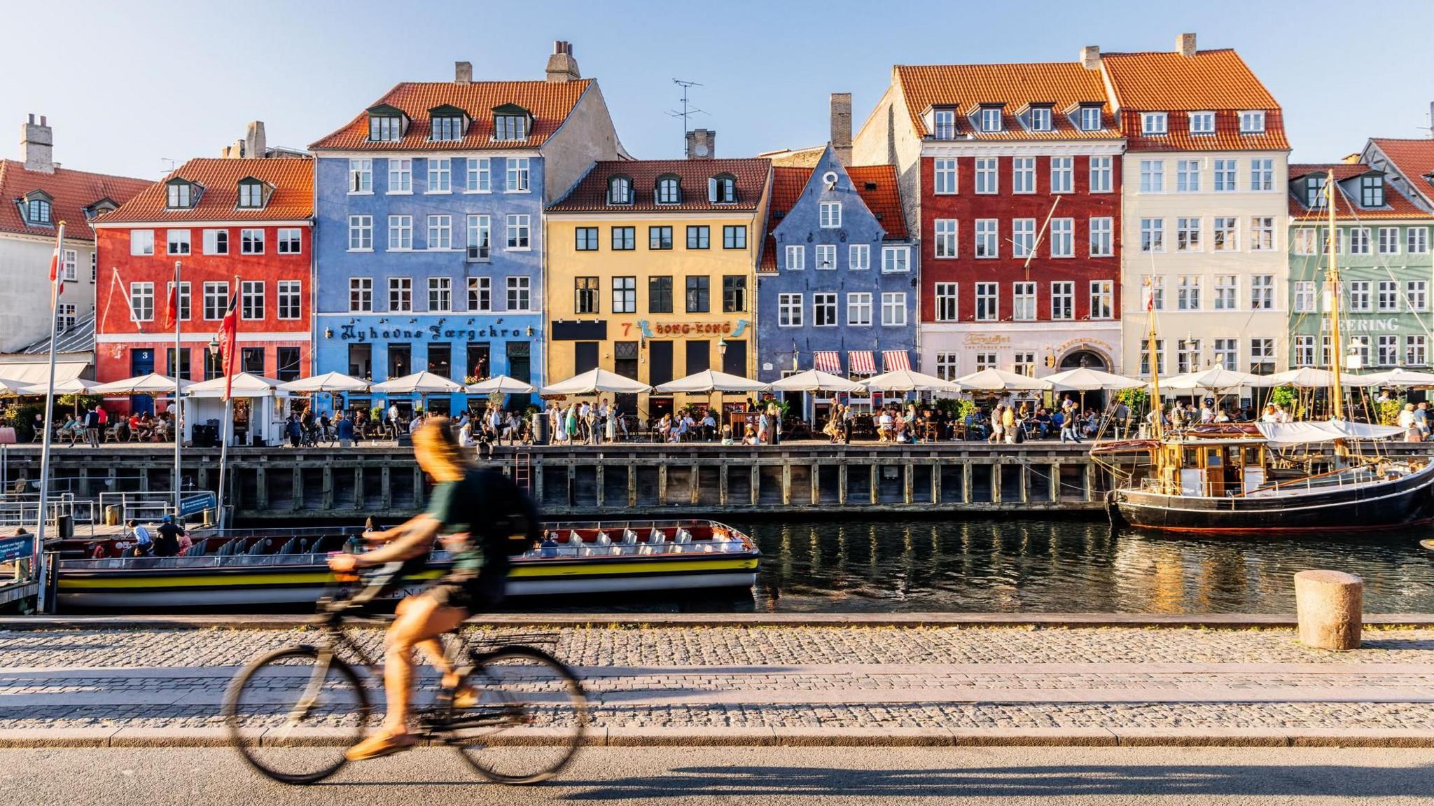 Nyhavn harbour with restaurants and crowds of tourists on a sunny summer day, Copenhagen, Denmark 