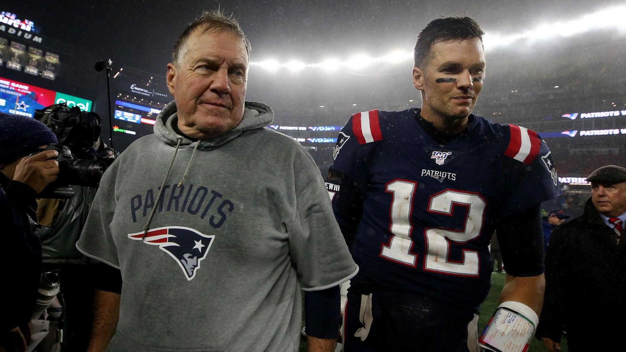 New England Patriots head coach Bill Belichick and quarterback Tom Brady leave the field surrounded by cameras