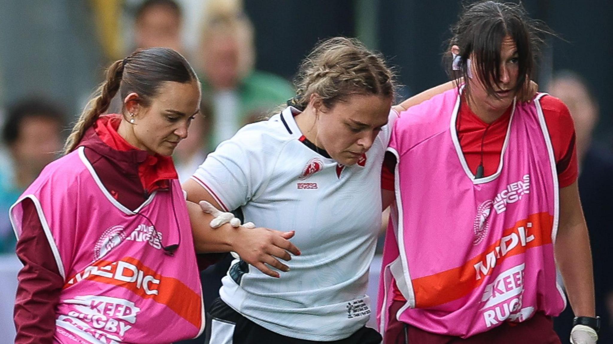 Jenni Scoble (C) is helped off against Canada