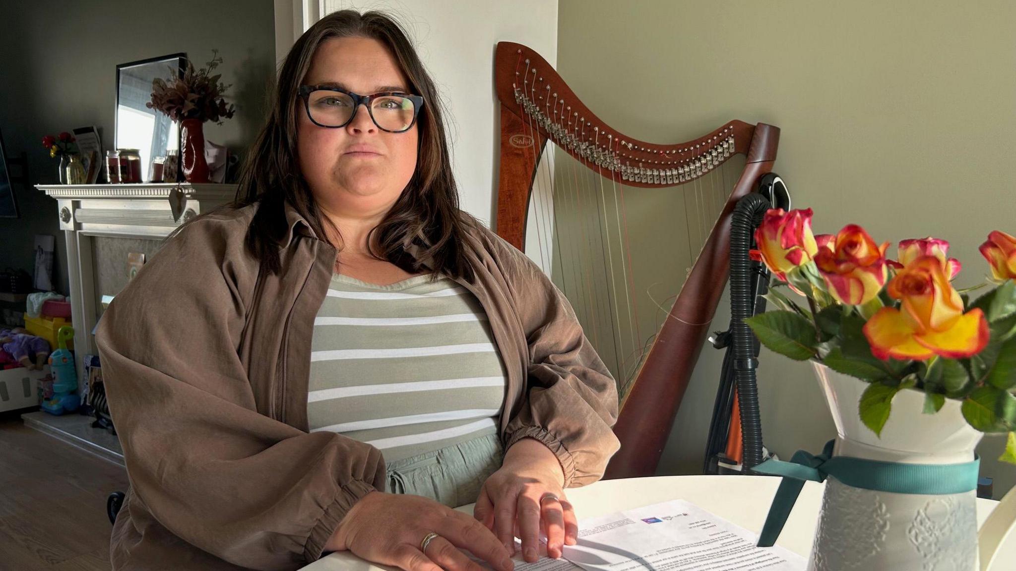 Gabriella Smith yn eistedd wrth fwrdd y gegin, gyda llythyrau o'r banciau a PM Property Law