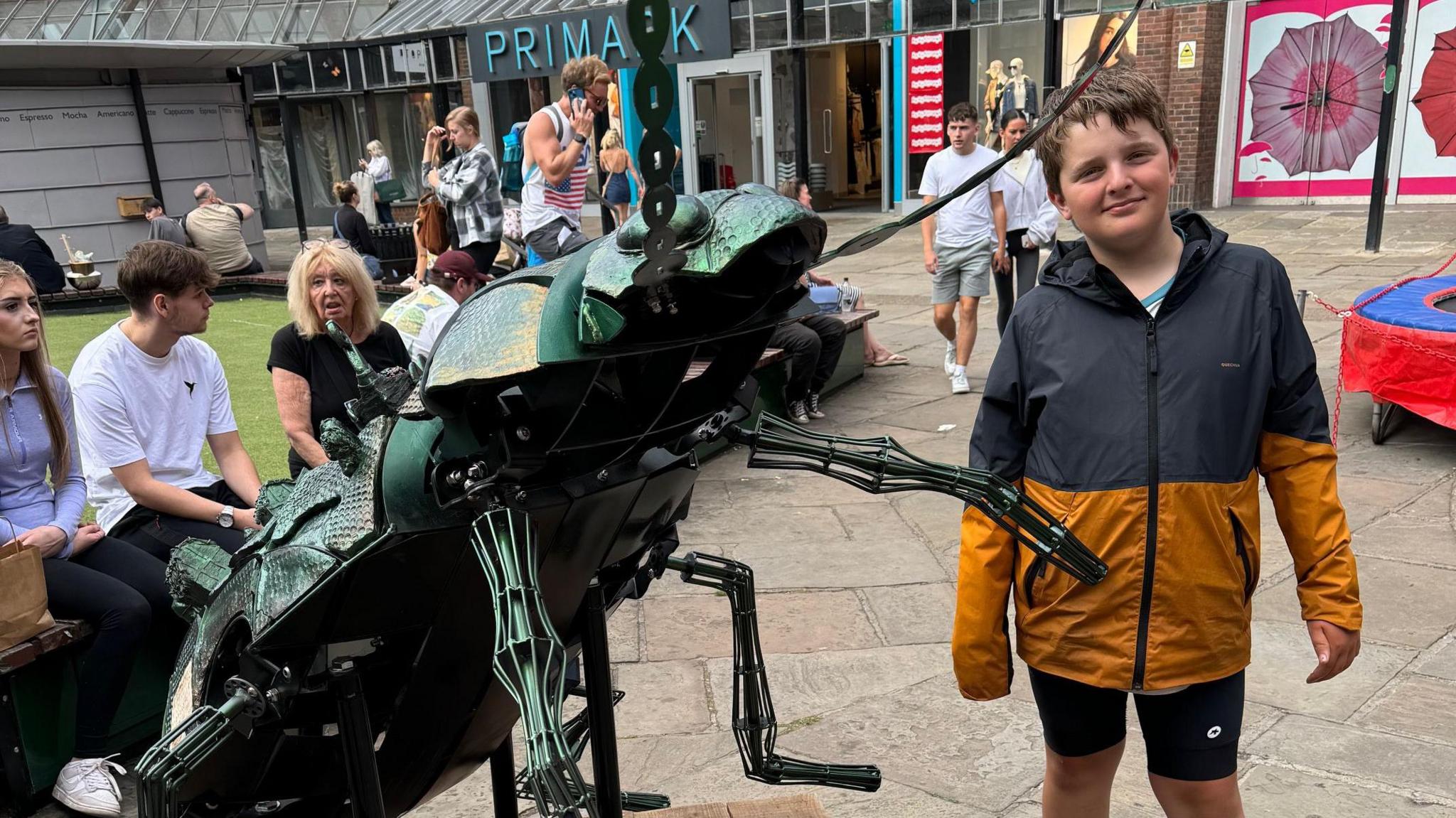 Harry poses with a large metal insect sculpture