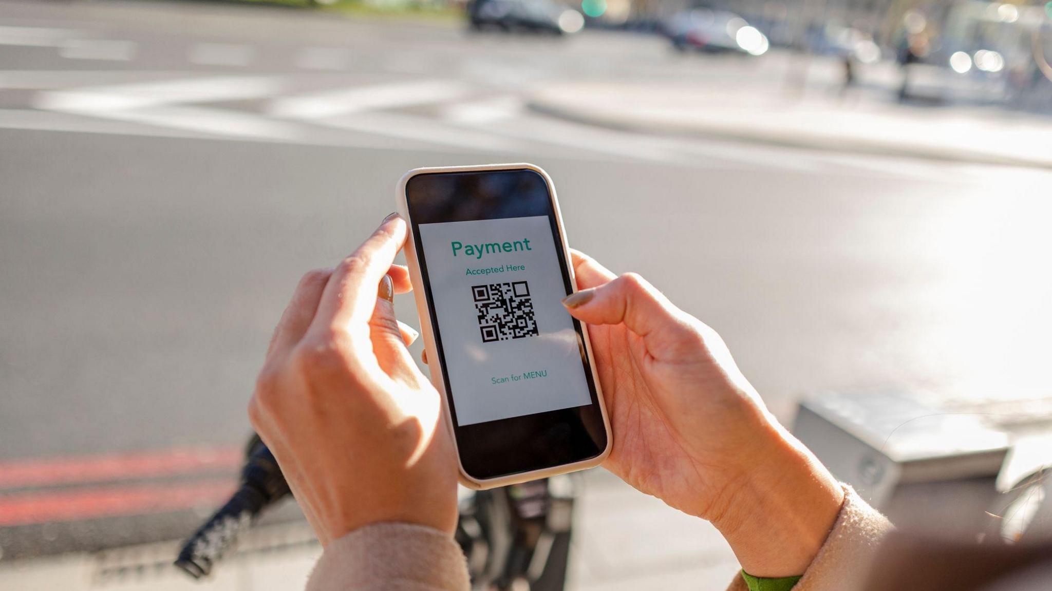 Woman holding a phone with a payment QR code on the screen