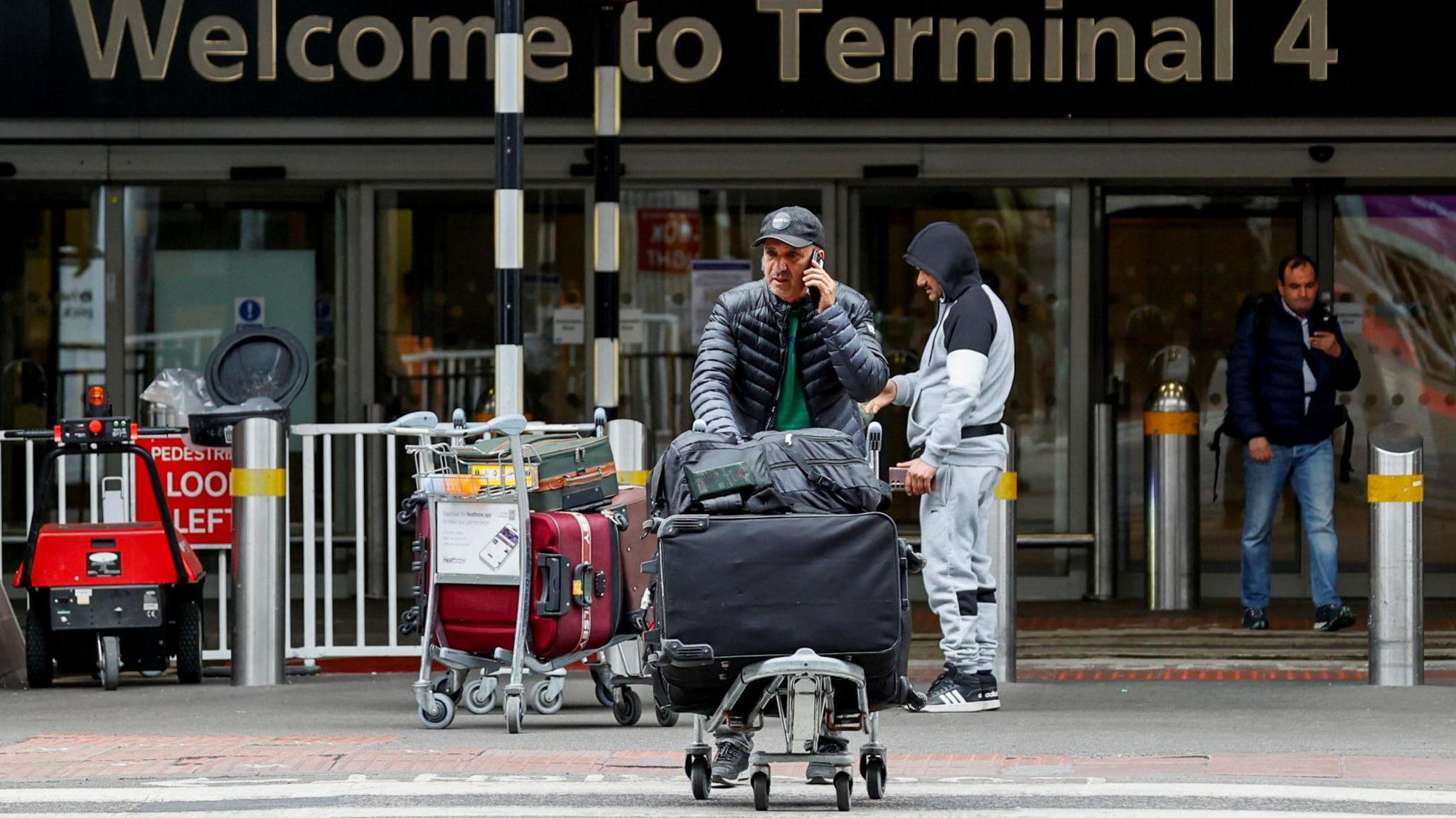 Teithiwr yn cerdded y tu allan i Faes Awyr Rhyngwladol Heathrow