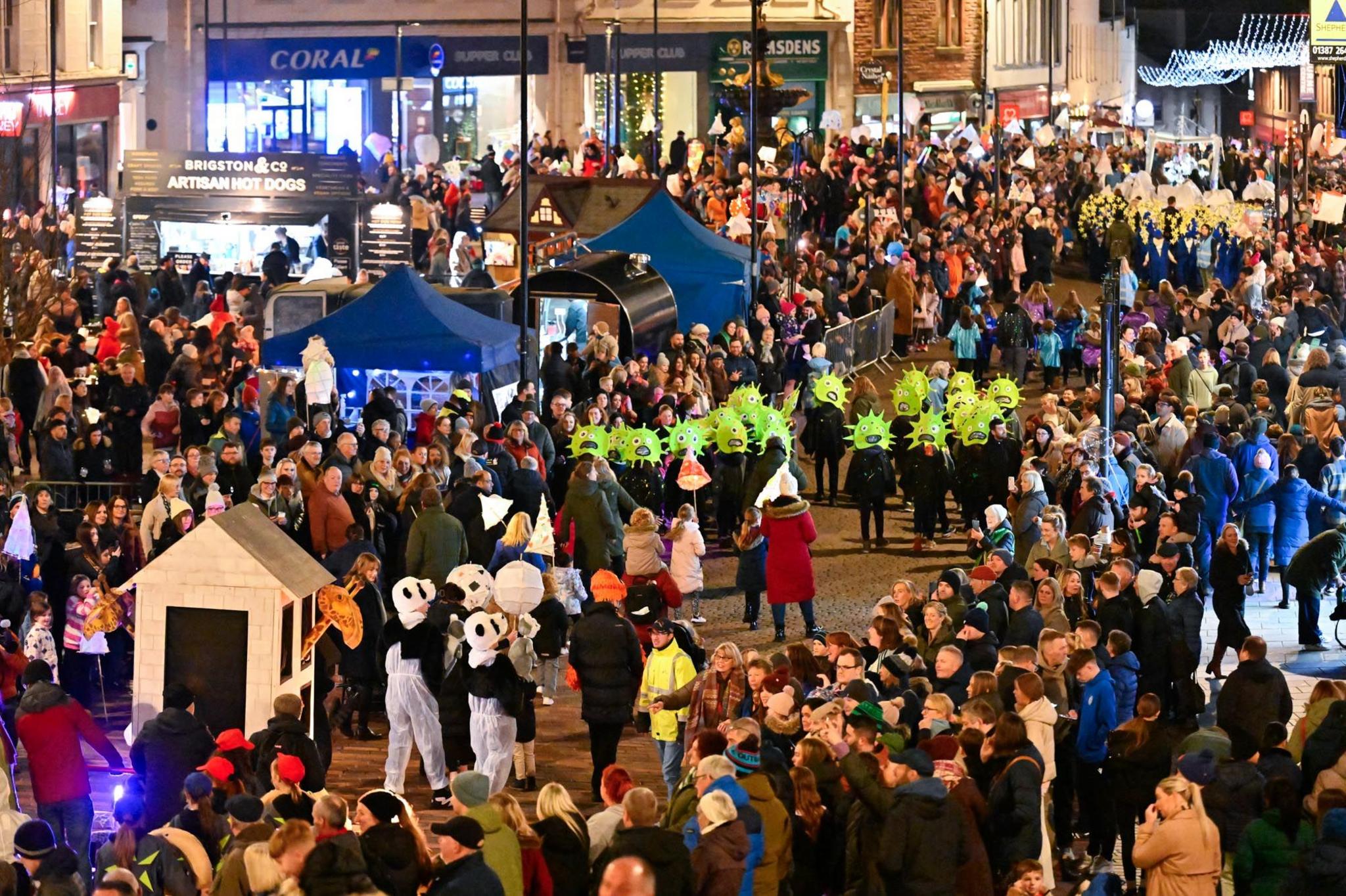 A view down Dumfries high street with a colourful parade passing through and big crowds lining the streets