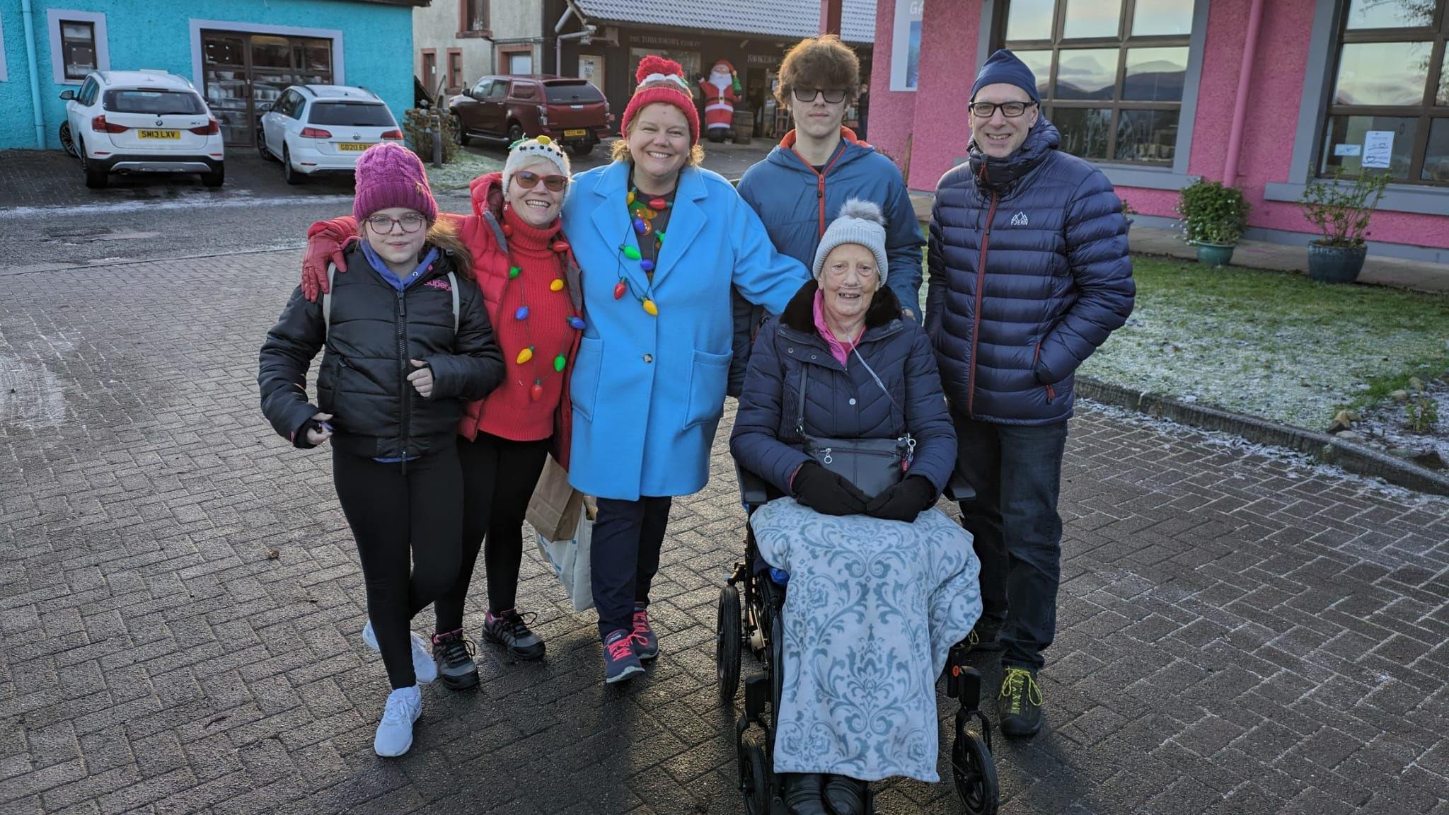 Margo Baxter ann an cathair-chuibhle leis an teaghlach aice 